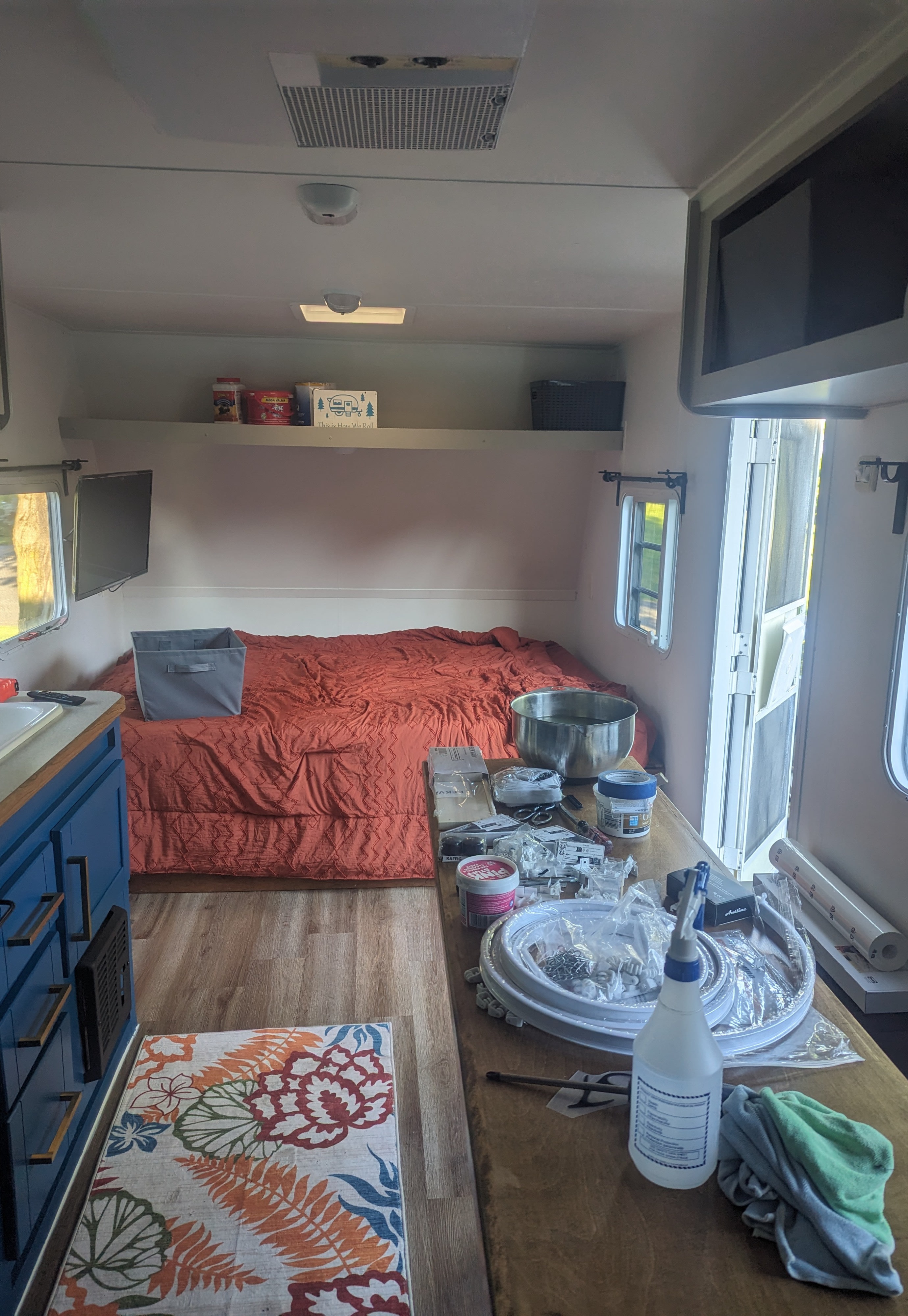 RV rental interior: a cozy bed, blue kitchen cabinets, and a work table filled with tools and renovation supplies.. Gulf Stream Ameri-Lite 2004