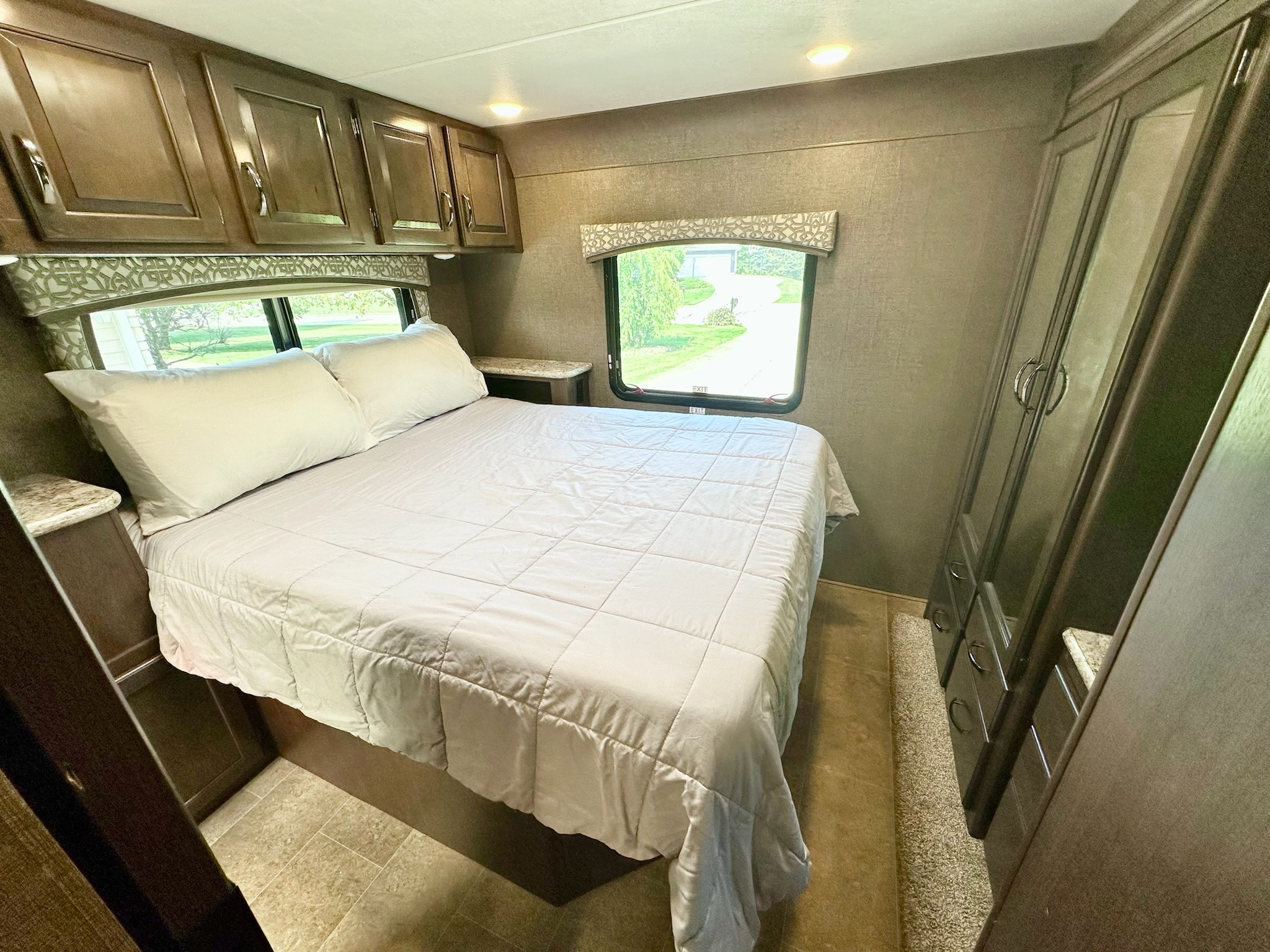 RV rental's inviting bedroom: soft bed, ample overhead cabinets, large window view, and built-in wardrobe.. Thor Chateau 2019