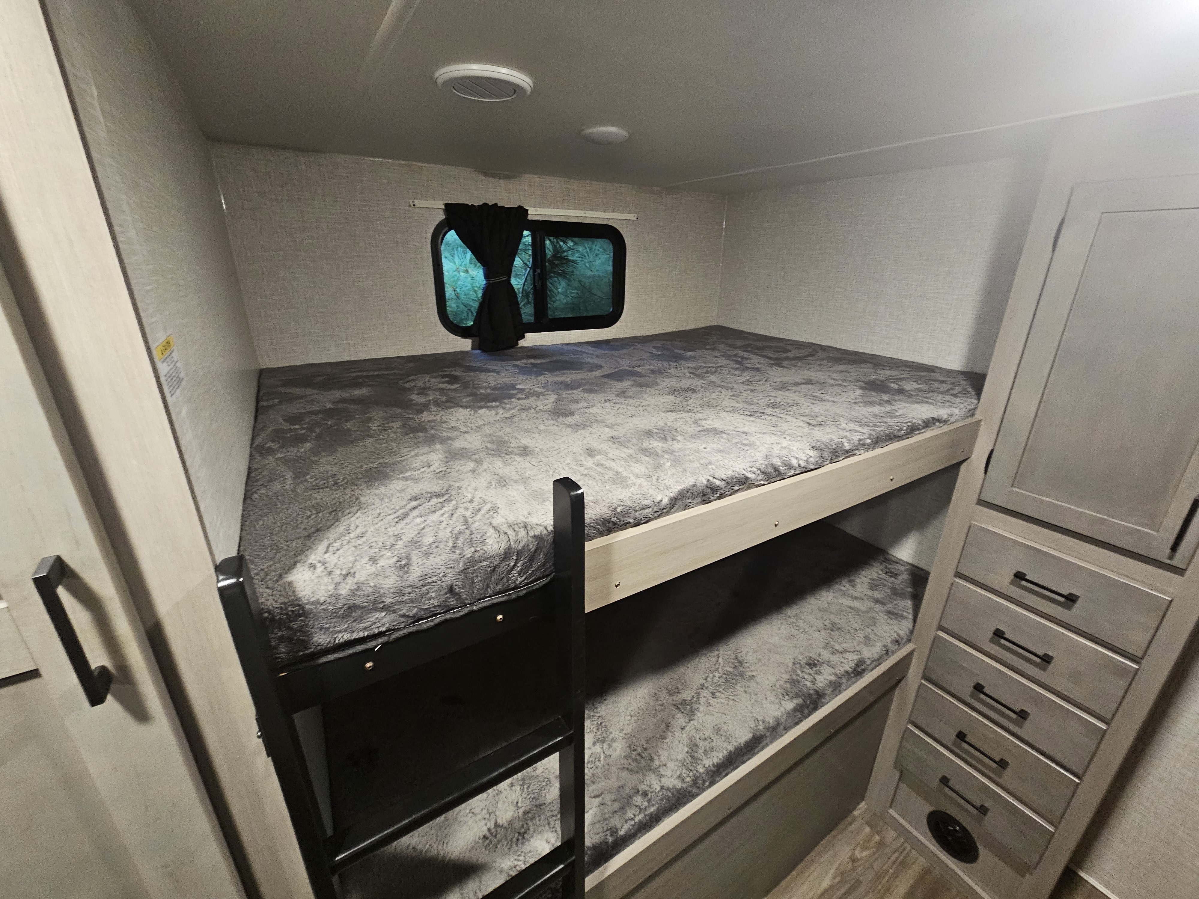 Interior of an RV rental bunkhouse, featuring cozy bunk beds with plush gray bedding, a window, and storage unit.. Starcraft GSL 2024