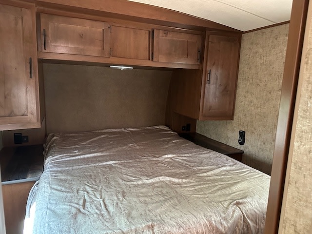 RV rental bedroom with wooden cabinets, a cozy bed, and practical storage.. Outdoors RV Timber Ridge 2020
