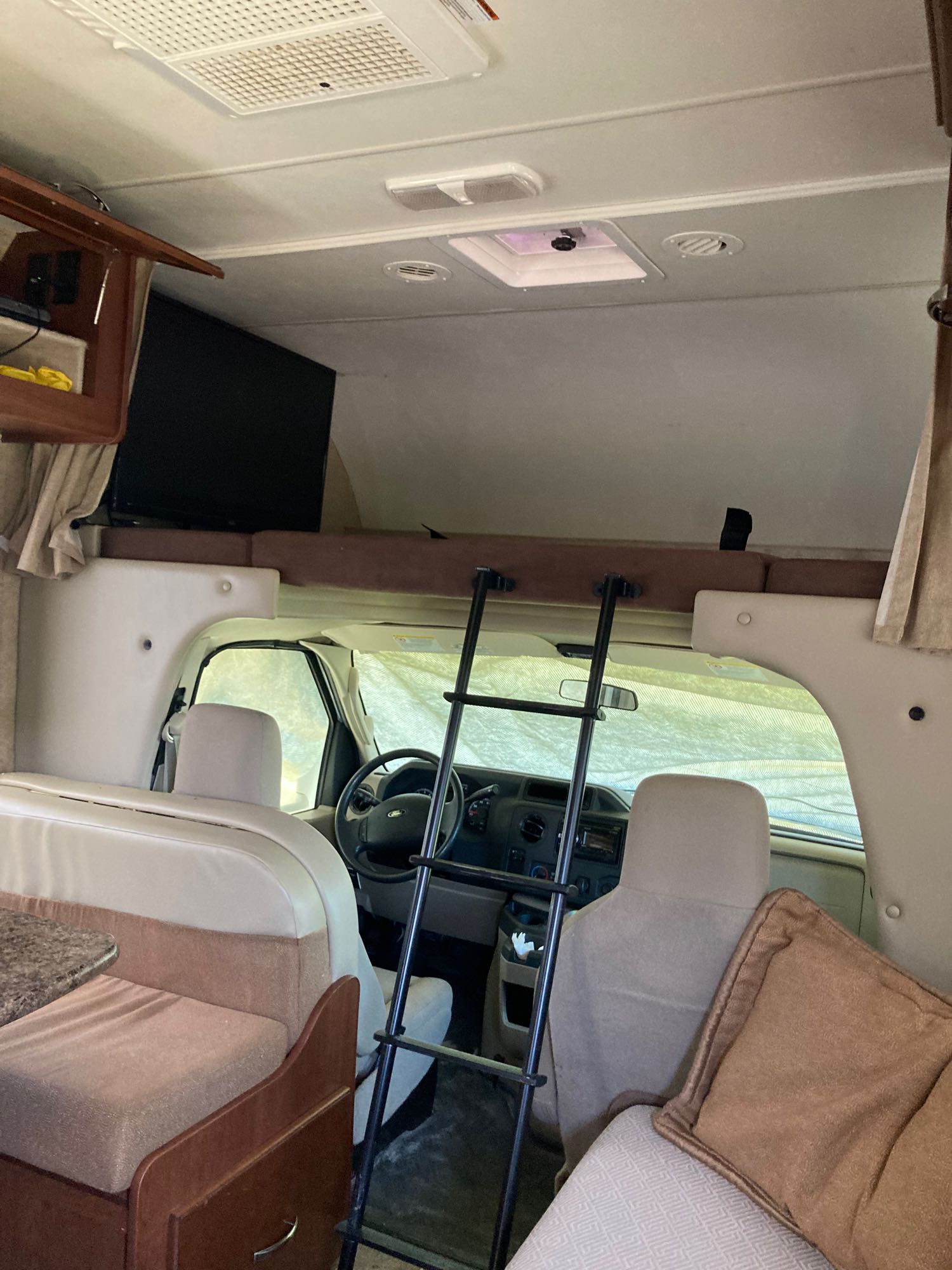 Explore this rv rental's cozy interior, showing the cockpit, overhead bunk with ladder, and dining area, ready for adventure.. Thor Four Winds 2016