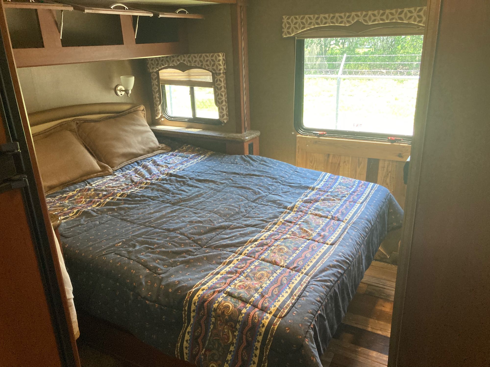 RV rental bedroom: a large bed with patterned comforter & brown pillows. Built-in storage & bright windows for natural light.. Thor Four Winds 2016