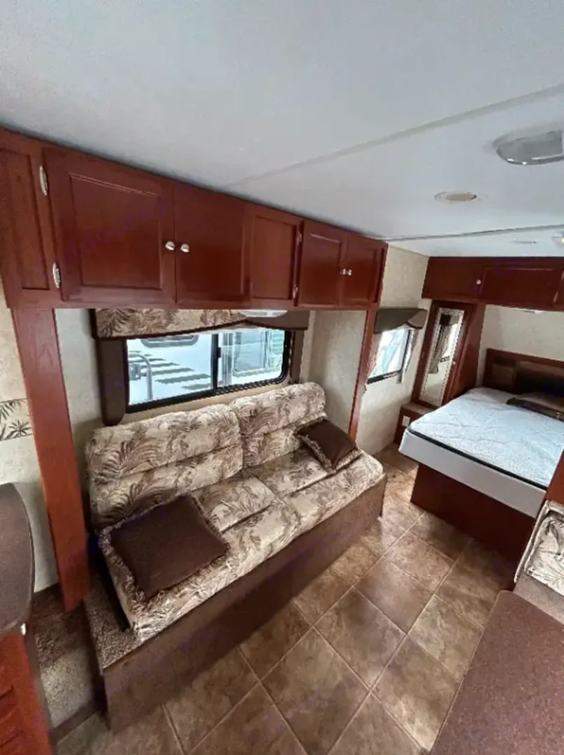 RV rental interior showcasing a living area with a sofa and a bedroom with a comfortable bed and storage.. Dutchmen Kodiak 2010