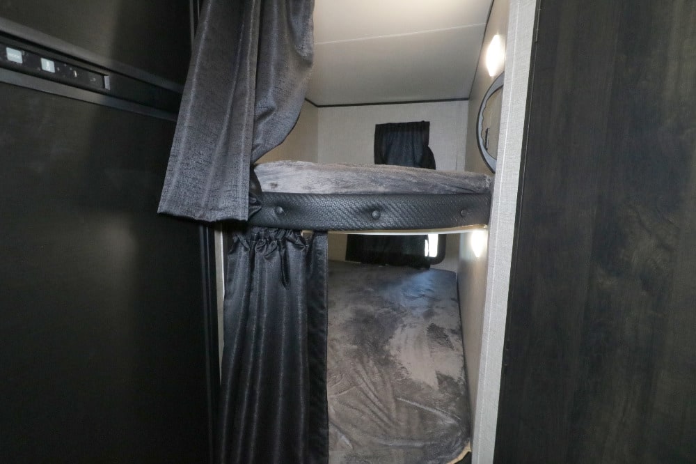 Inside an RV rental, discover dark gray bunk beds with curtains for privacy, offering a compact sleeping space.. Jayco Jay Flight SLX Rocky Mountain Edition 2022