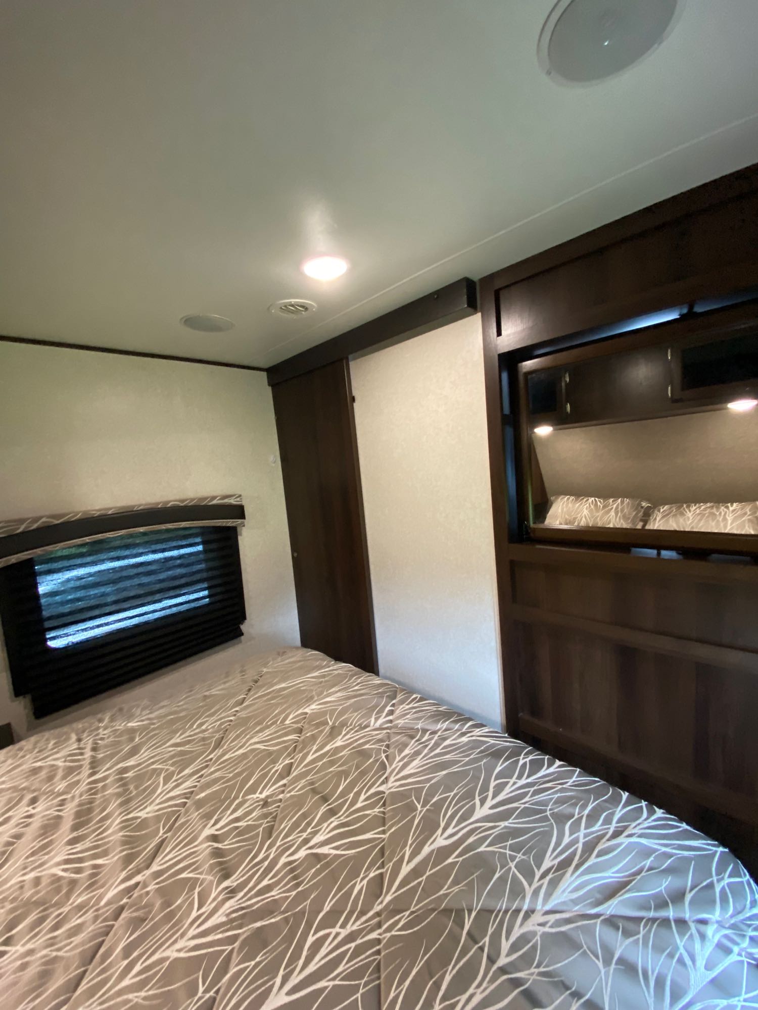 Modern RV rental bedroom featuring a comfortable bed, window, and stylish dark wood cabinetry.. Jayco Jay Flight 2018