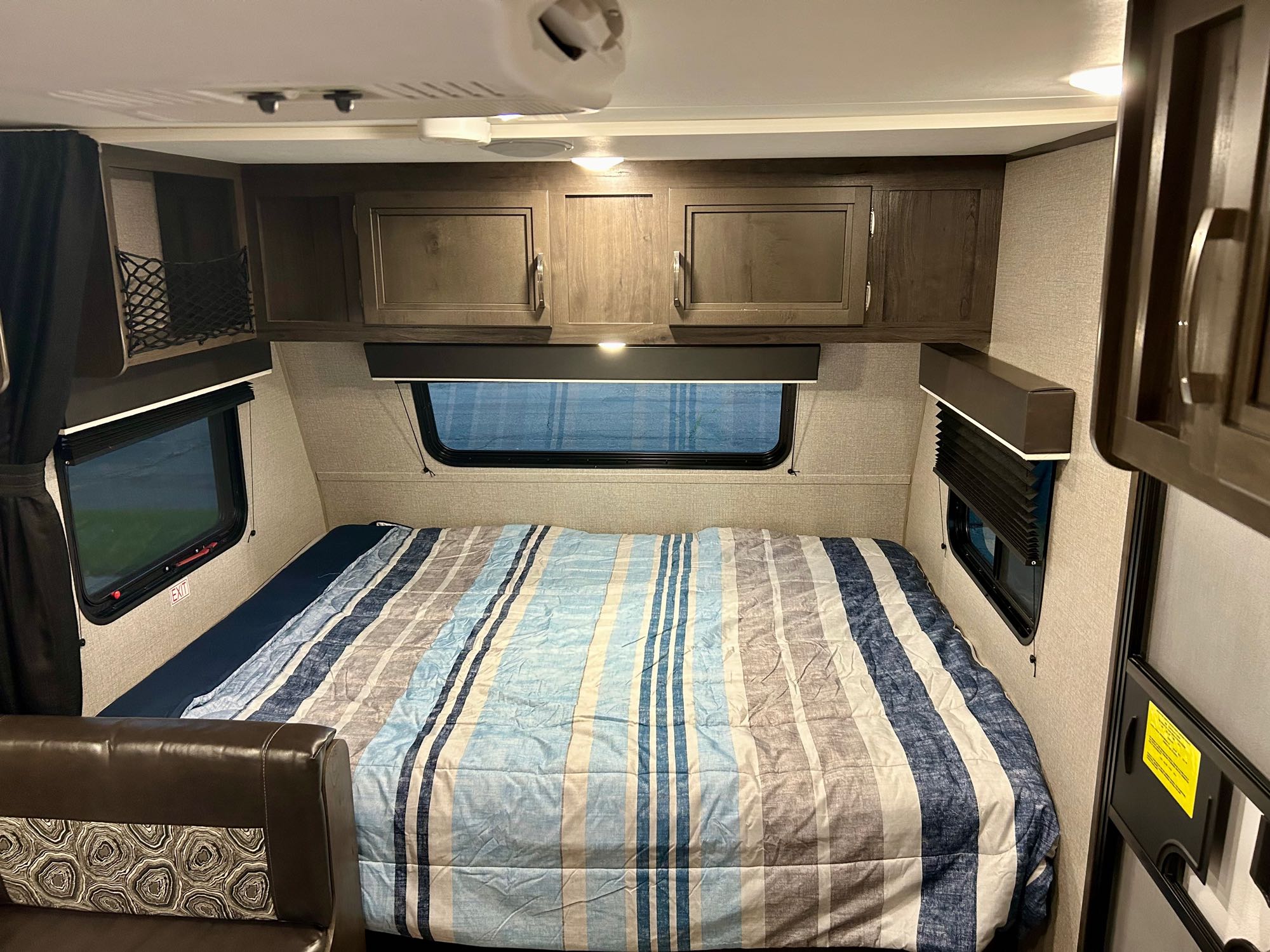 Comfortable RV rental bedroom with striped comforter, overhead storage, and large windows. Perfect for your next trip.. Jayco Jay Flight SLX 2020
