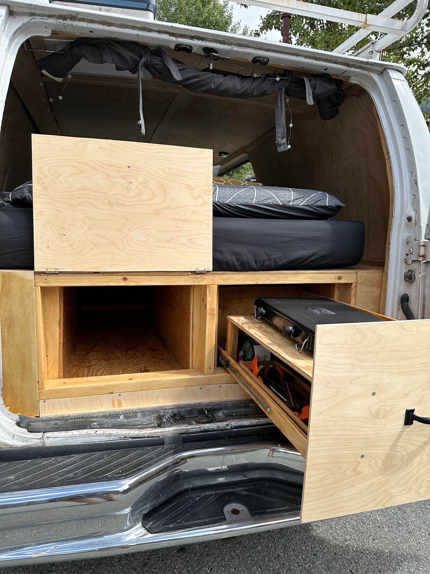 Inside an RV rental conversion: custom bed, pull-out kitchen, and smart storage maximize van life adventures.. Ford Econolline 250s 2003