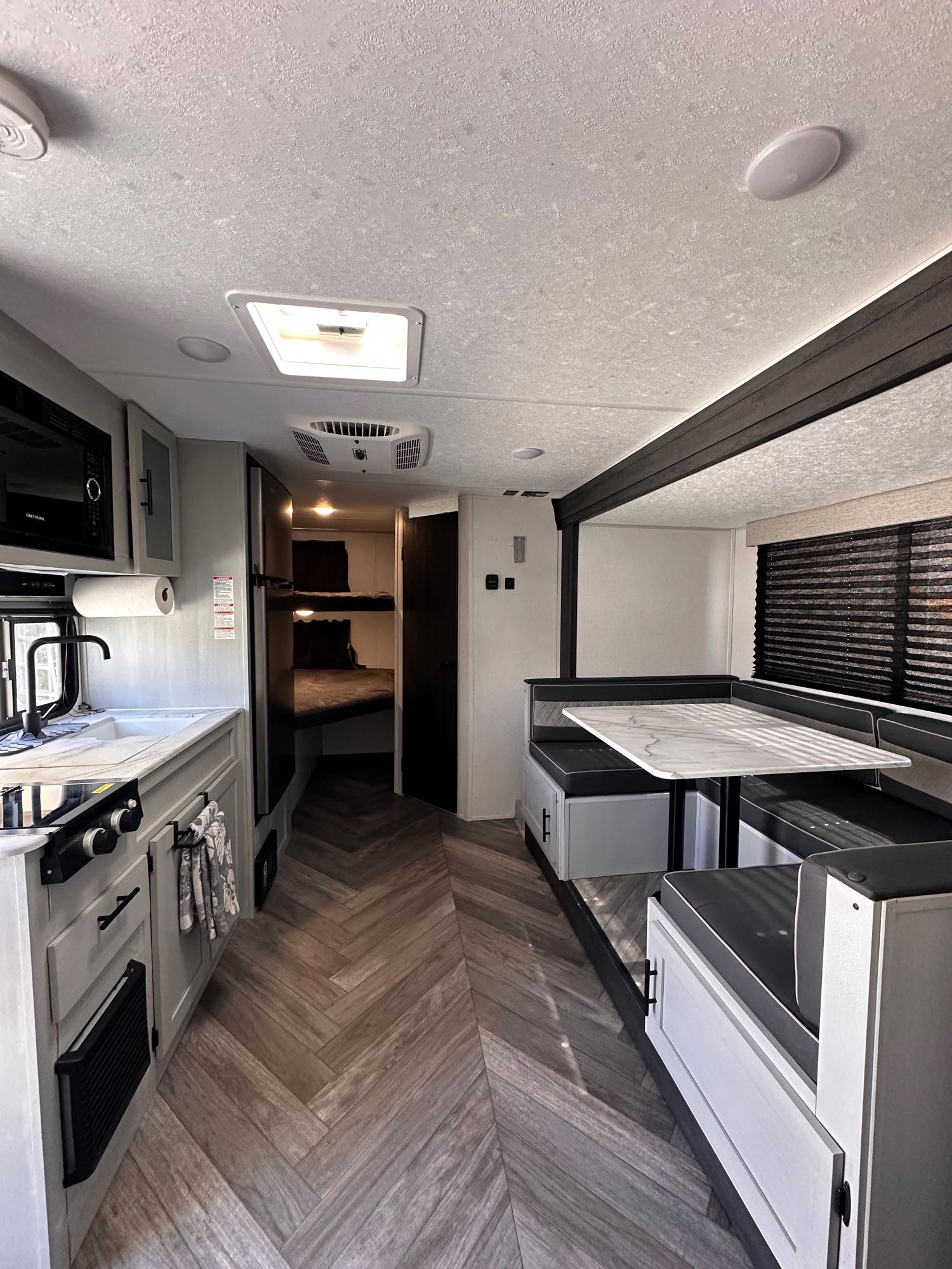 Bright rv rental interior showcases a modern kitchen, comfortable dining area with a table, and bunk beds in the rear.. Forest River Salem FSX Plantium 2022