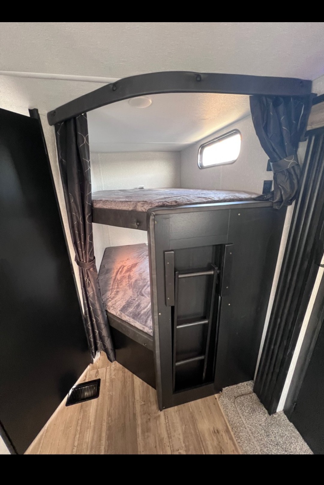 Comfortable bunk beds with a built-in ladder and window inside an RV rental, offering cozy sleeping space for travelers.. Forest River Cherokee 2022
