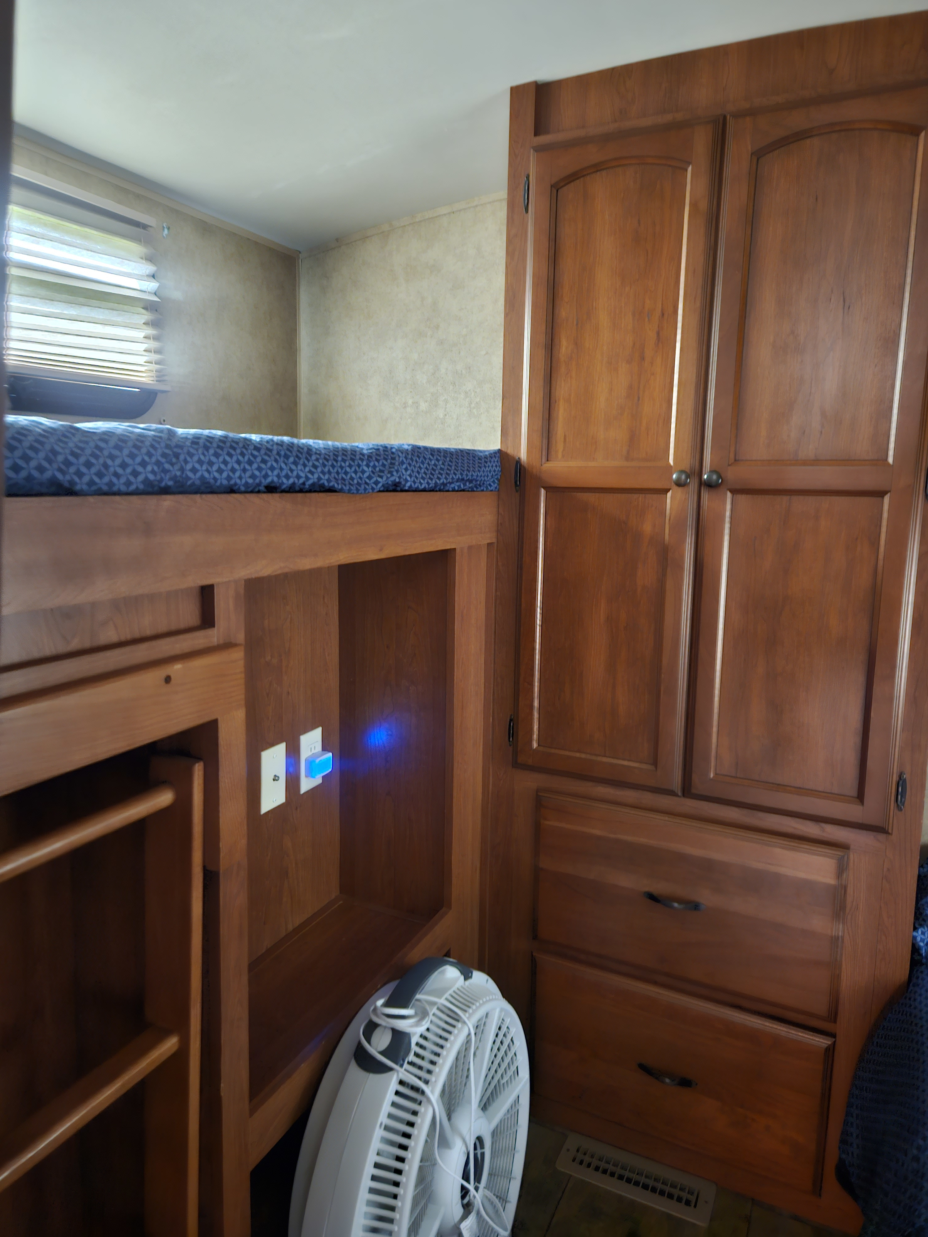 Cozy RV rental interior featuring a bunk bed, wooden cabinets, and a fan for comfort, plus a blue night light.. Dutchmen Aerolite 2013