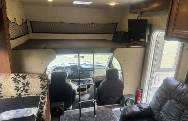 RV rental interior features an overhead bunk with ladder, cockpit, TV, and living area with seating for your journey.. Jamboree Searcher 2014