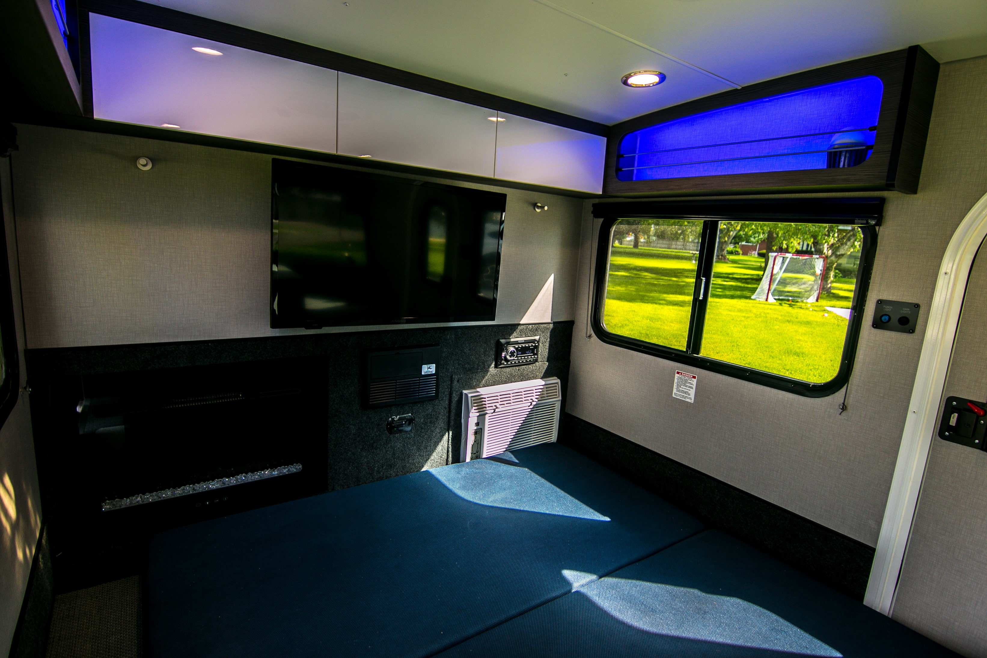 Modern rv rental interior with a cozy bed, TV, AC, and sleek storage. Bright lighting creates a welcoming space.. InTech RV Luna 2022