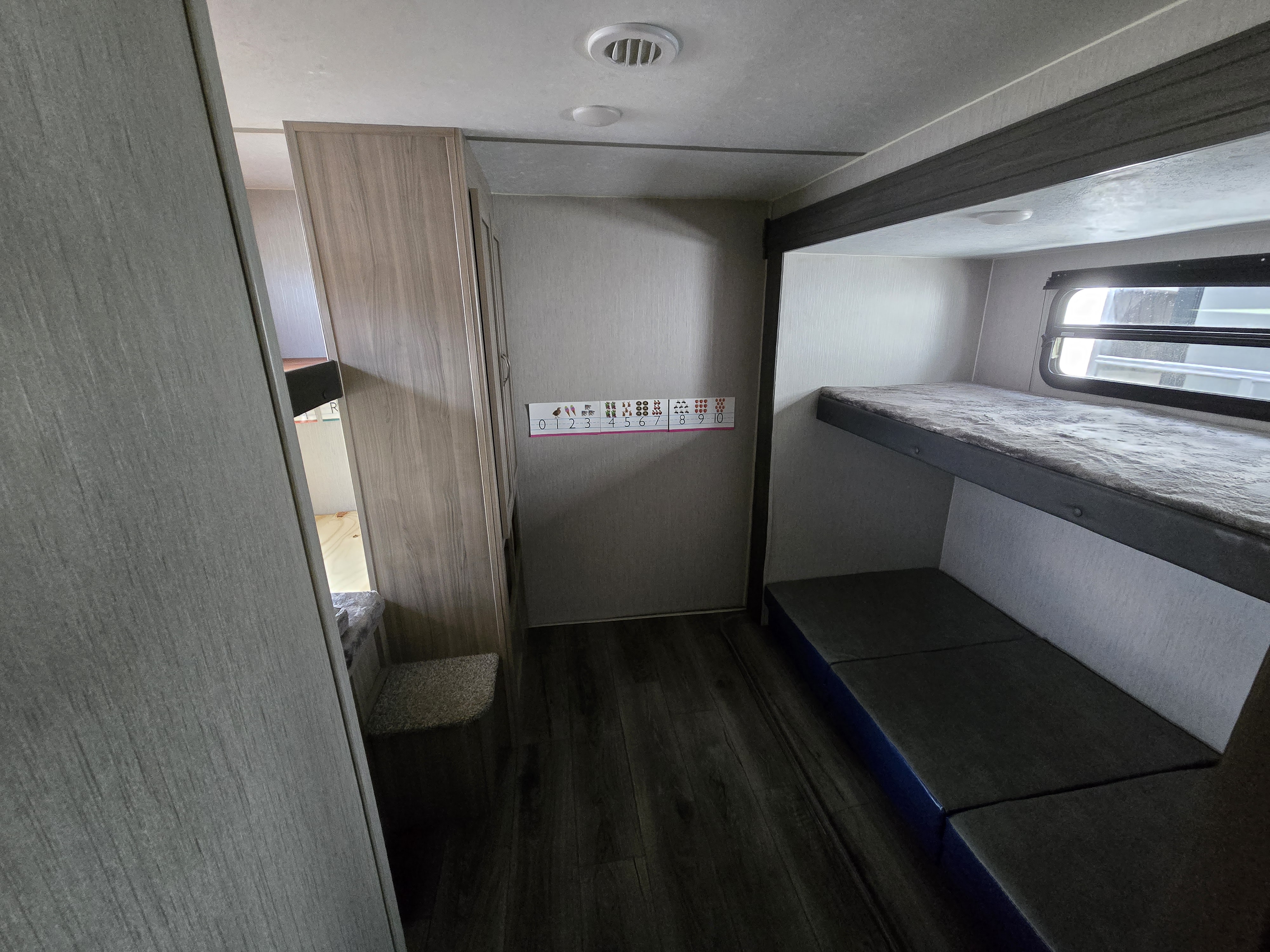RV rental interior: bunk beds, storage, and dark wood-look floor define this functional living space.. Coachmen Freedom Express 2022