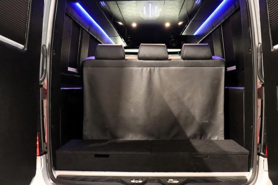 Luxury RV rental van interior: Rear view of black seating, blue LED lighting, and a storage bench.. Mercedes-Benz Sprinter 2022