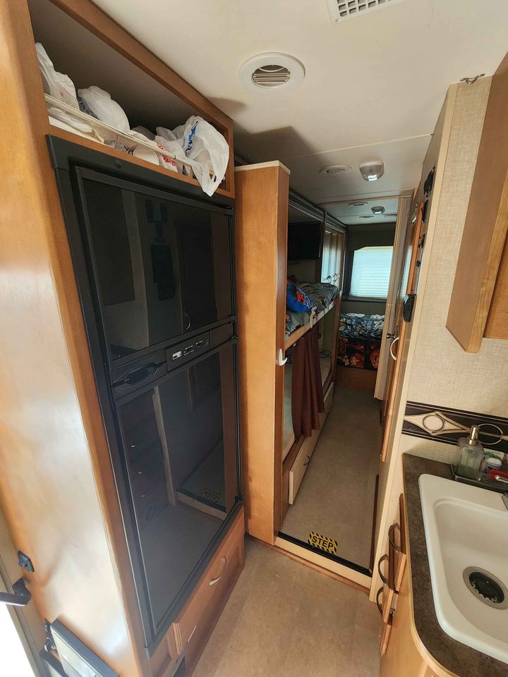 RV rental's cozy interior features a refrigerator, bunk beds, kitchen sink, and a floor step.. Winnebago Minnie Winnie 2016