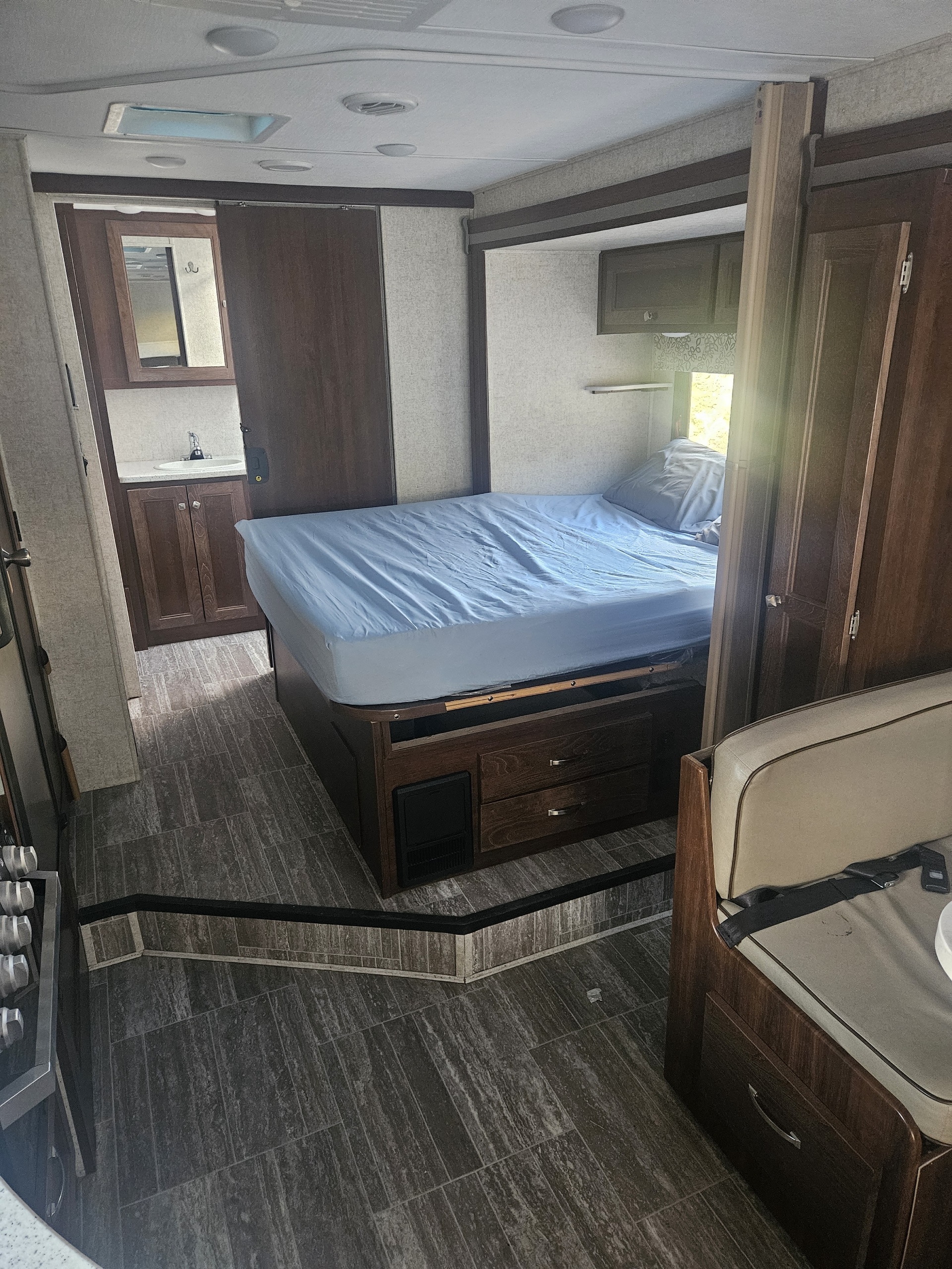 RV rental interior: A compact bedroom with built-in bed and storage, a small bathroom area, and a dinette seat.. Forester Forester Motorhome 2020
