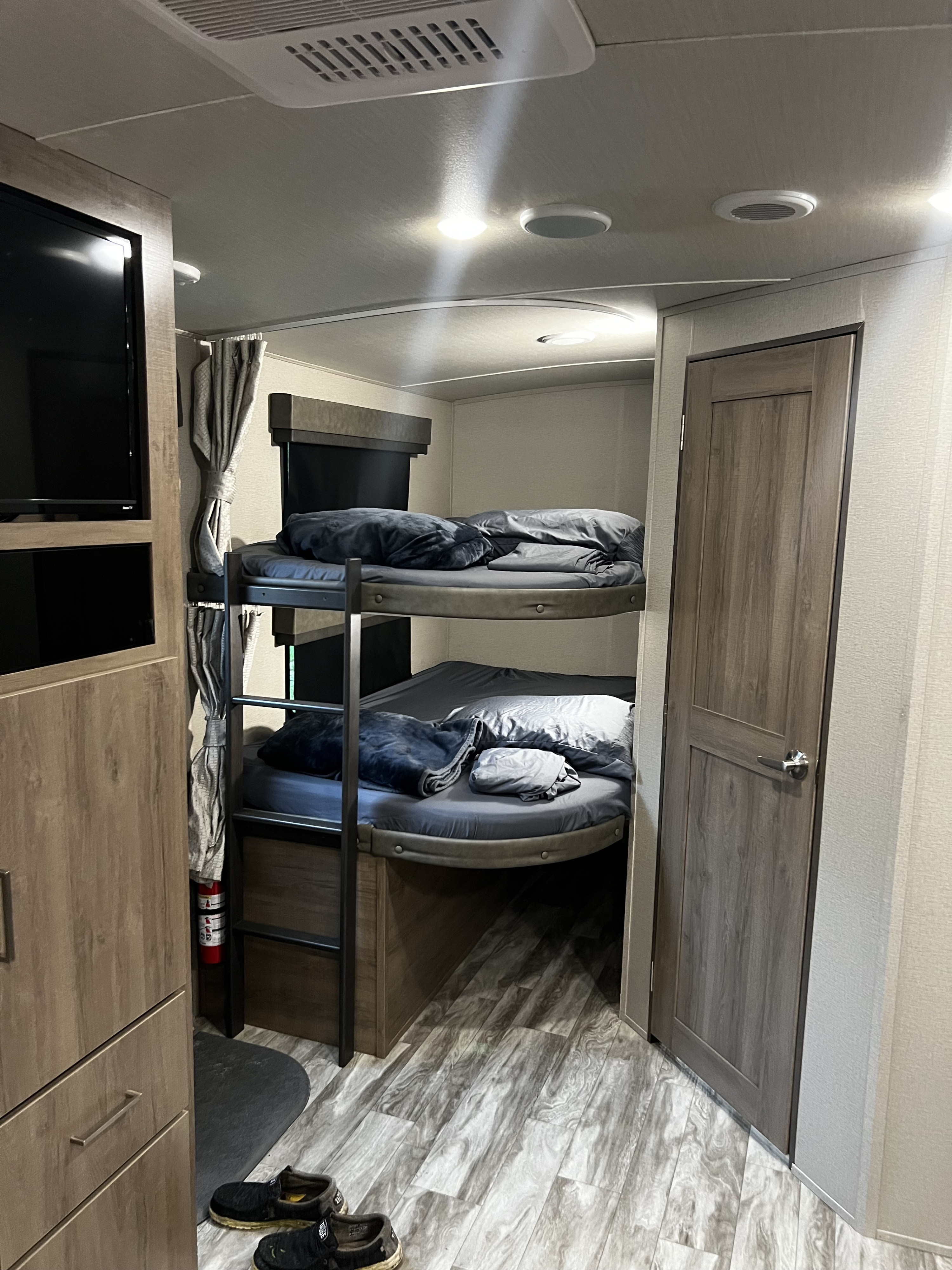 Cozy RV rental interior with bunk beds, TV, and wood-look flooring, perfect for family travel.. Grand Design Imagine 2022