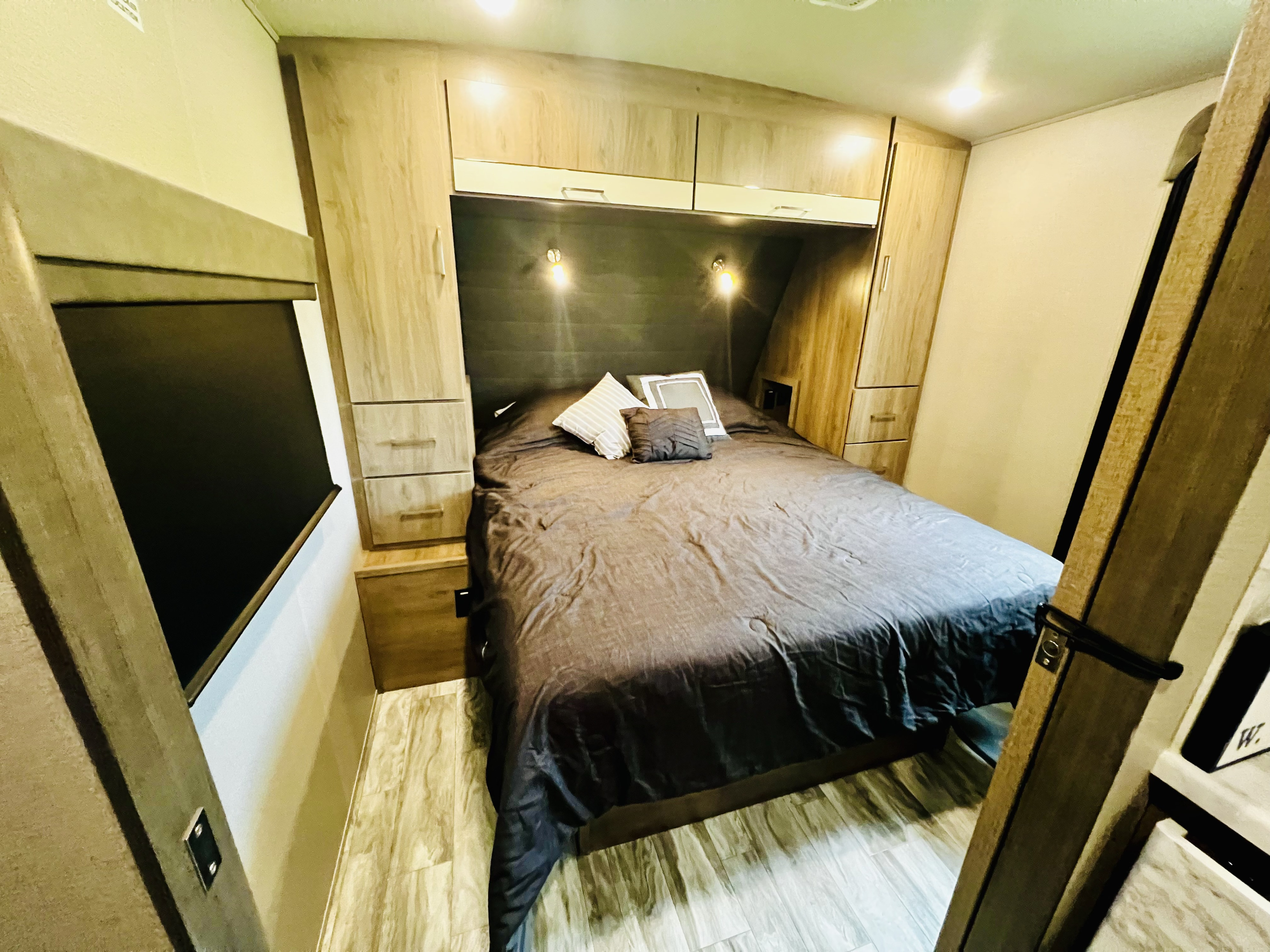 Relax in this RV rental bedroom: features a comfortable bed, built-in storage, and window for your travels.. Grand Design Imagine 2022