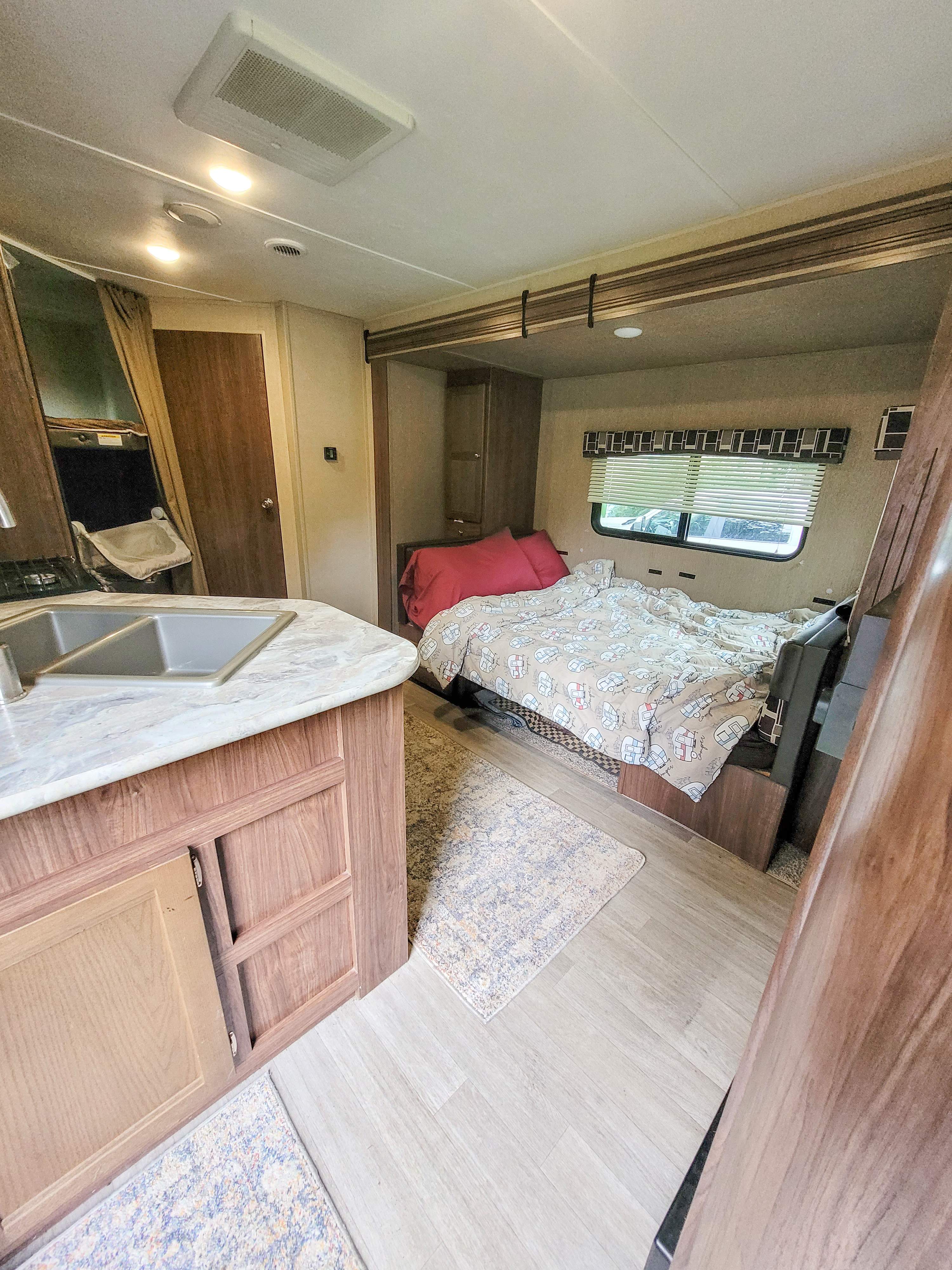 Spacious RV rental interior featuring a cozy bed, kitchen area, and light wood finishes. Perfect for travel comfort.. Dutchmen Coleman Lantern LT 2017