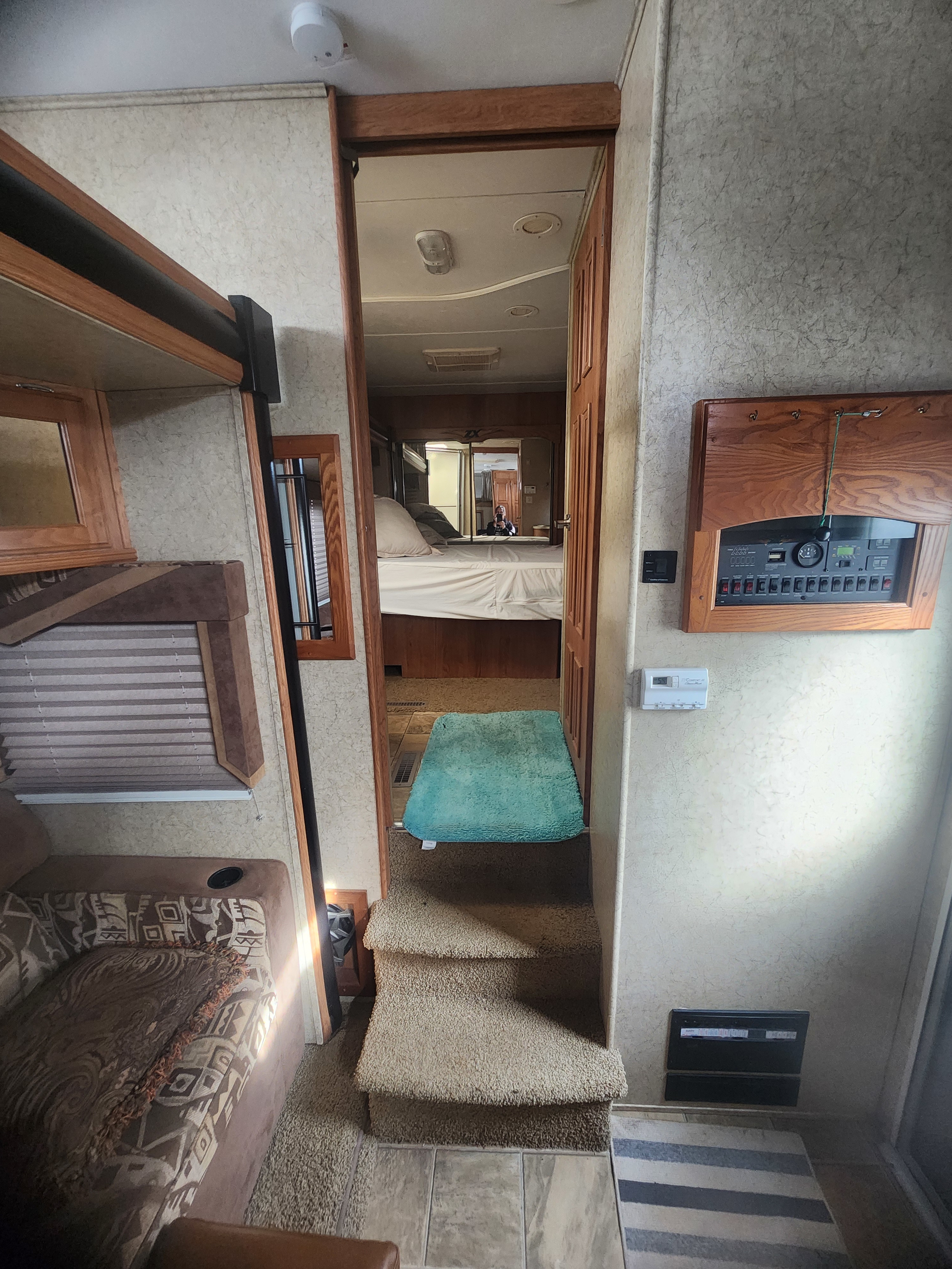 Inside an RV rental: Steps lead to the bedroom beyond, with a system control panel and upholstered seating. Ready for travel!. Jayco Recon Toy Hauler 2008