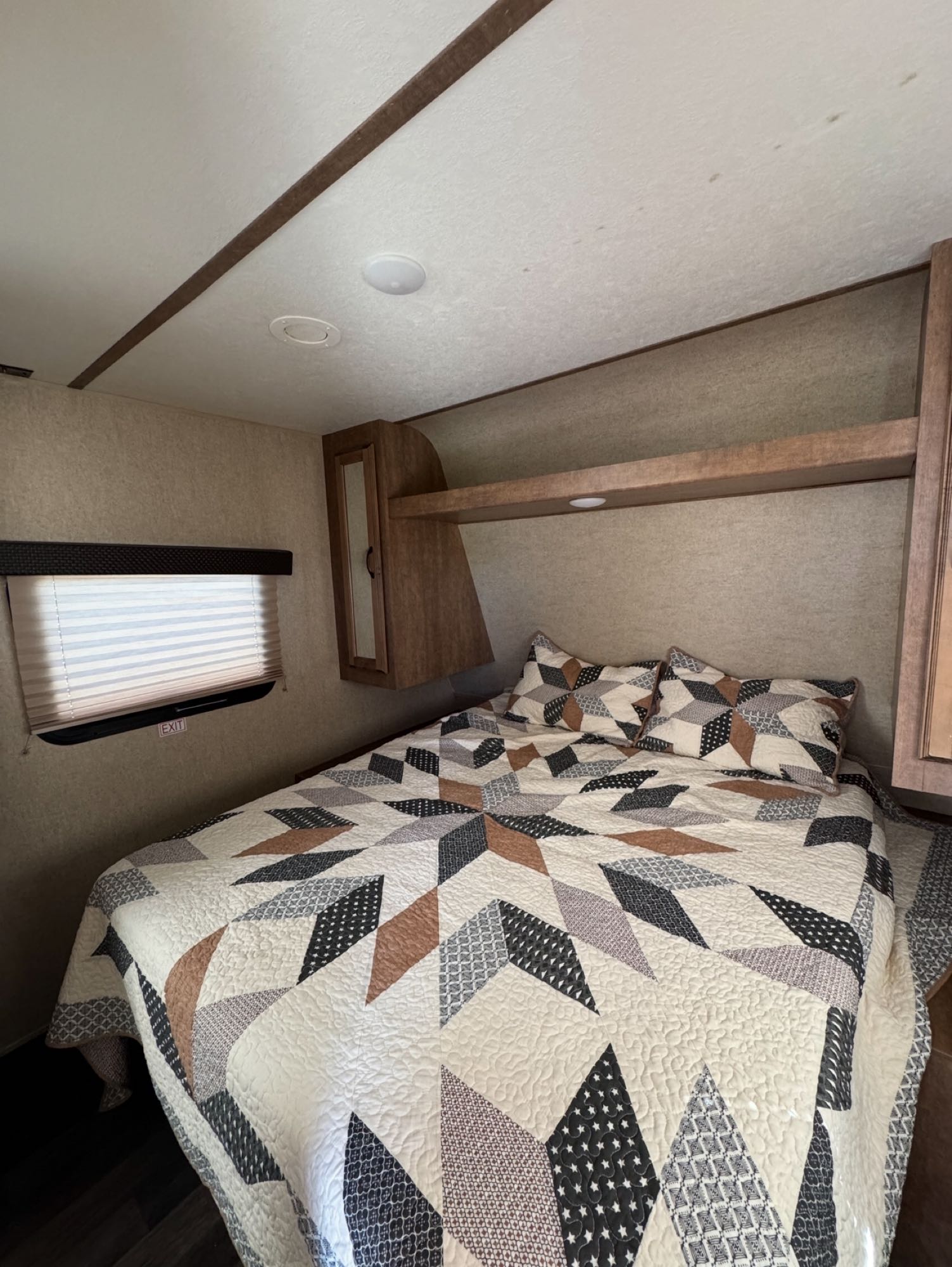 Cozy RV rental bedroom showcasing a patterned quilt, window with blinds, and built-in wood cabinetry, ready for your trip.. Starcraft Launch Outfitter 2018