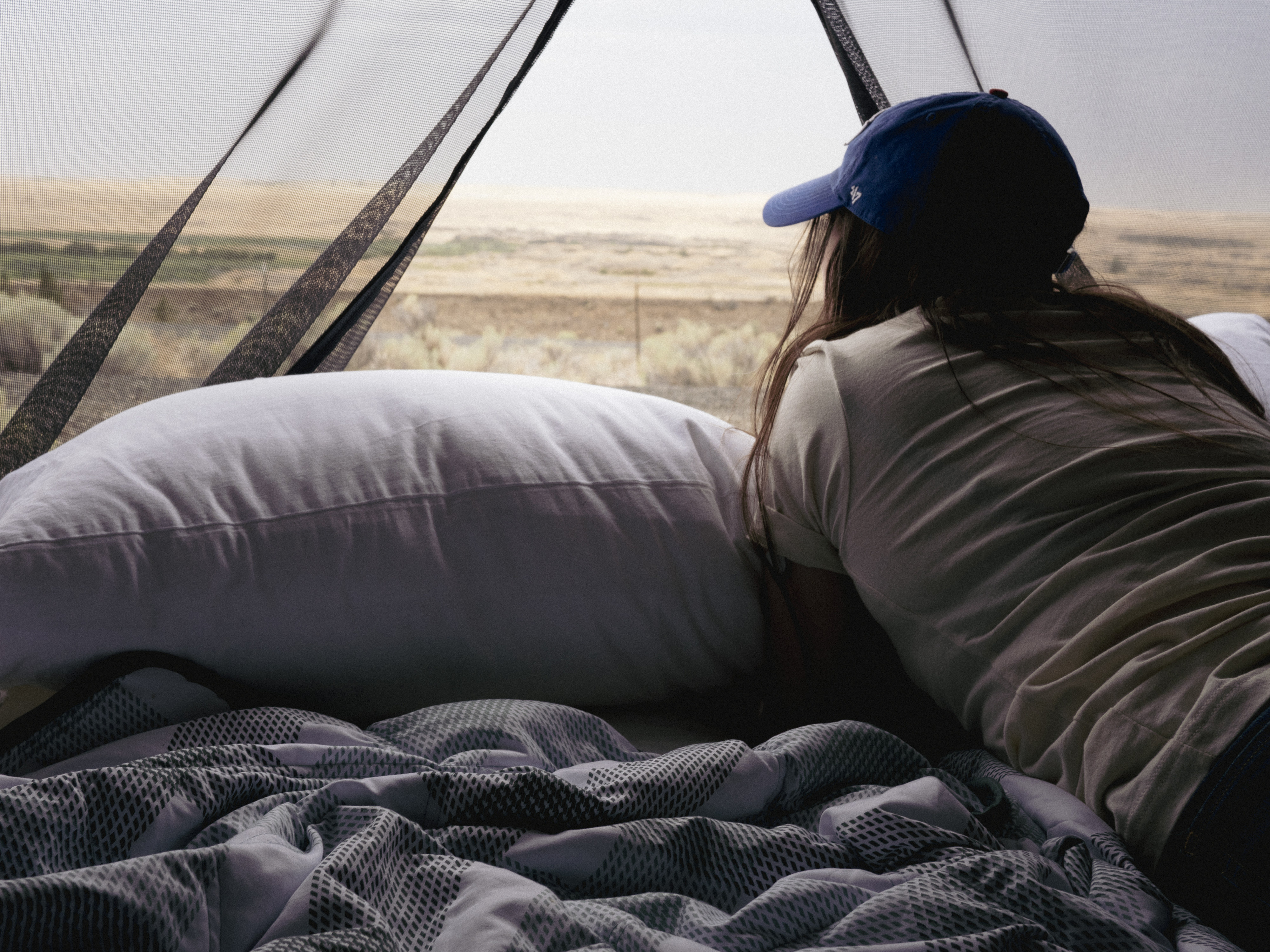Cozy RV rental stay: a traveler rests on soft bedding, enjoying the desert landscape through a screened window.. Other Other 2022