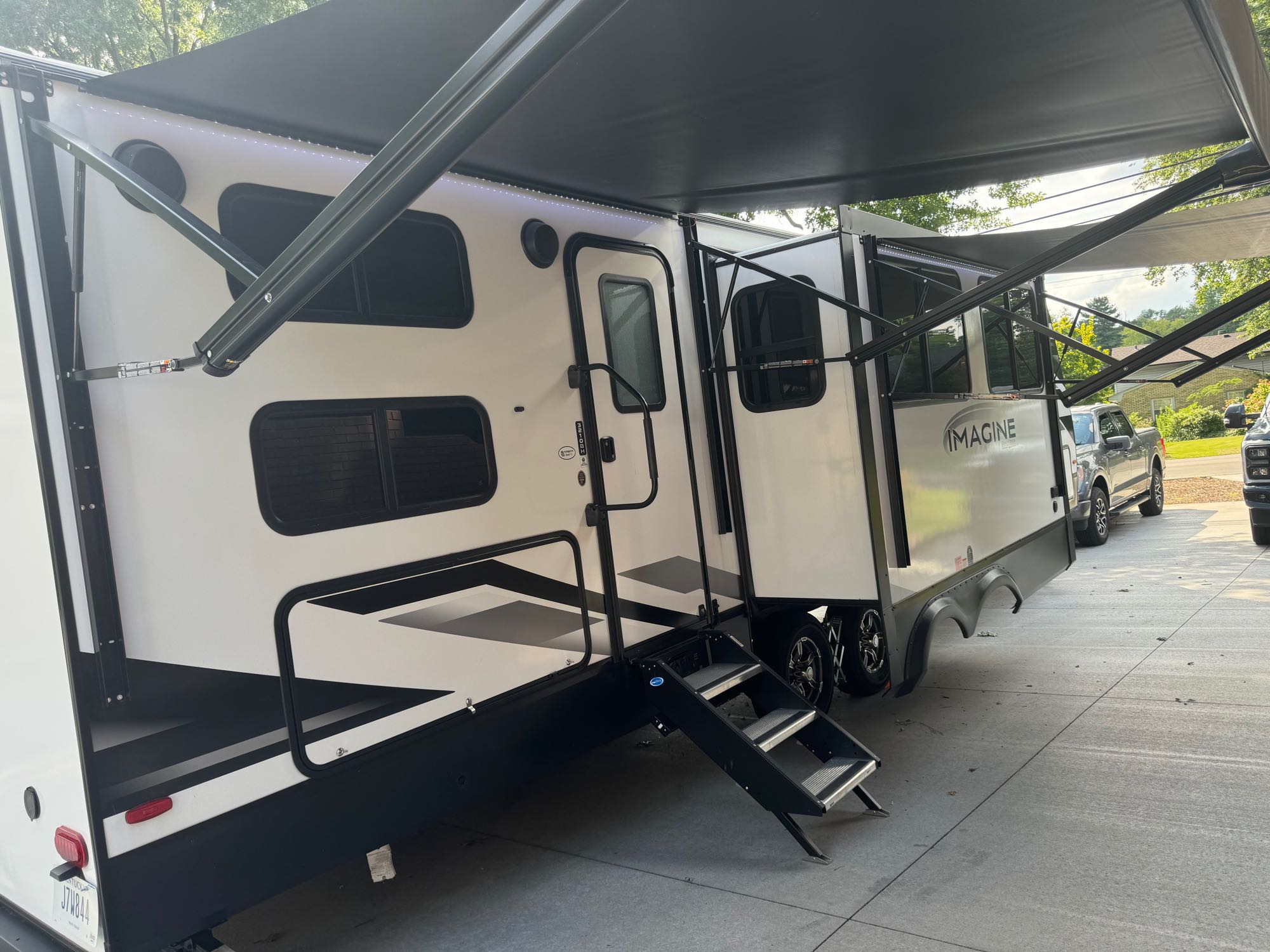 White Imagine travel trailer with an extended awning and entry steps. Perfect for your RV rental getaway.. Grand Design Imagine 3210BH 2023