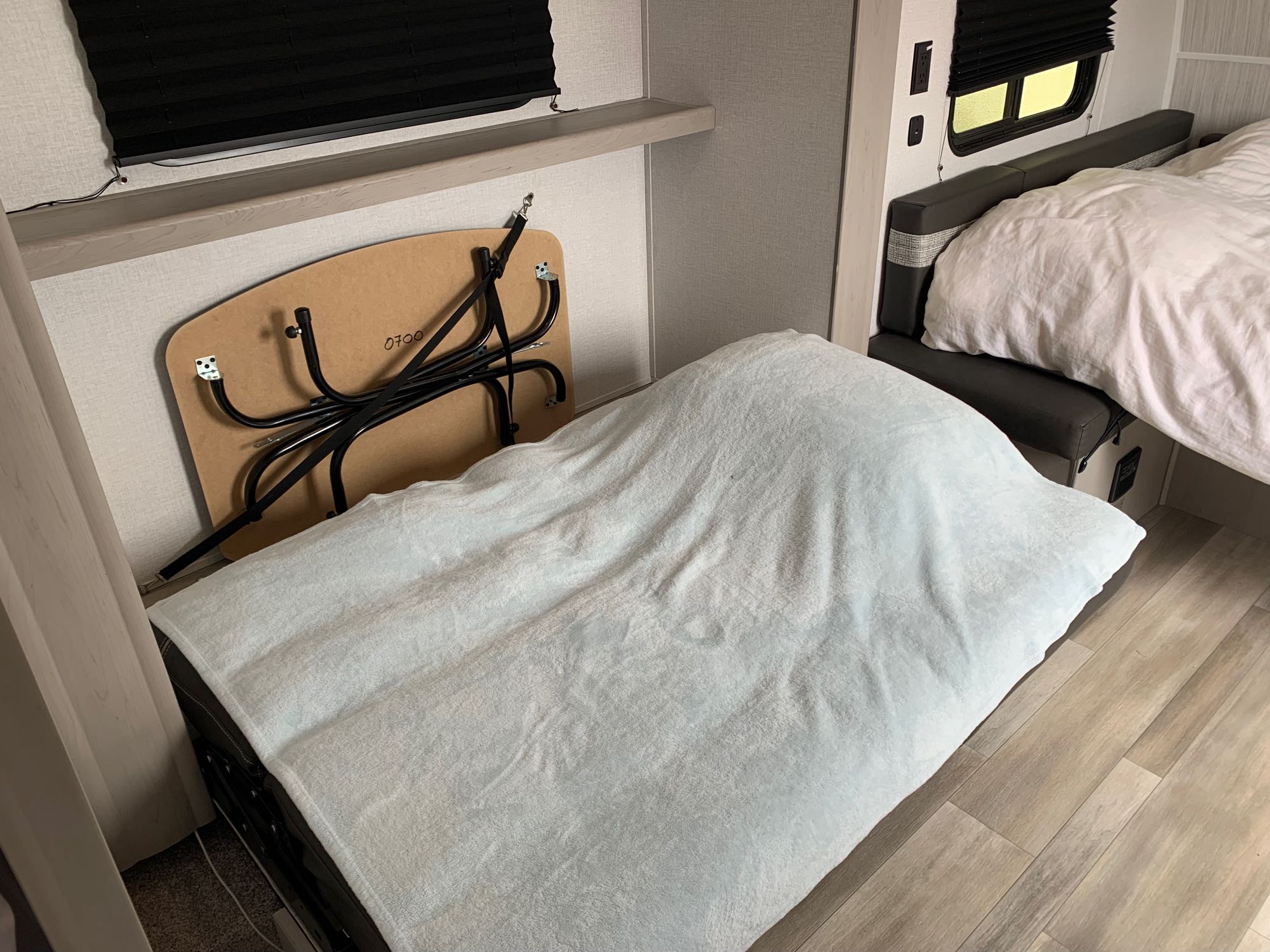 RV rental interior: A light blue blanket covers a dinette bed. Another bed with white linens is to the right.. Clipper 18BHS 2023