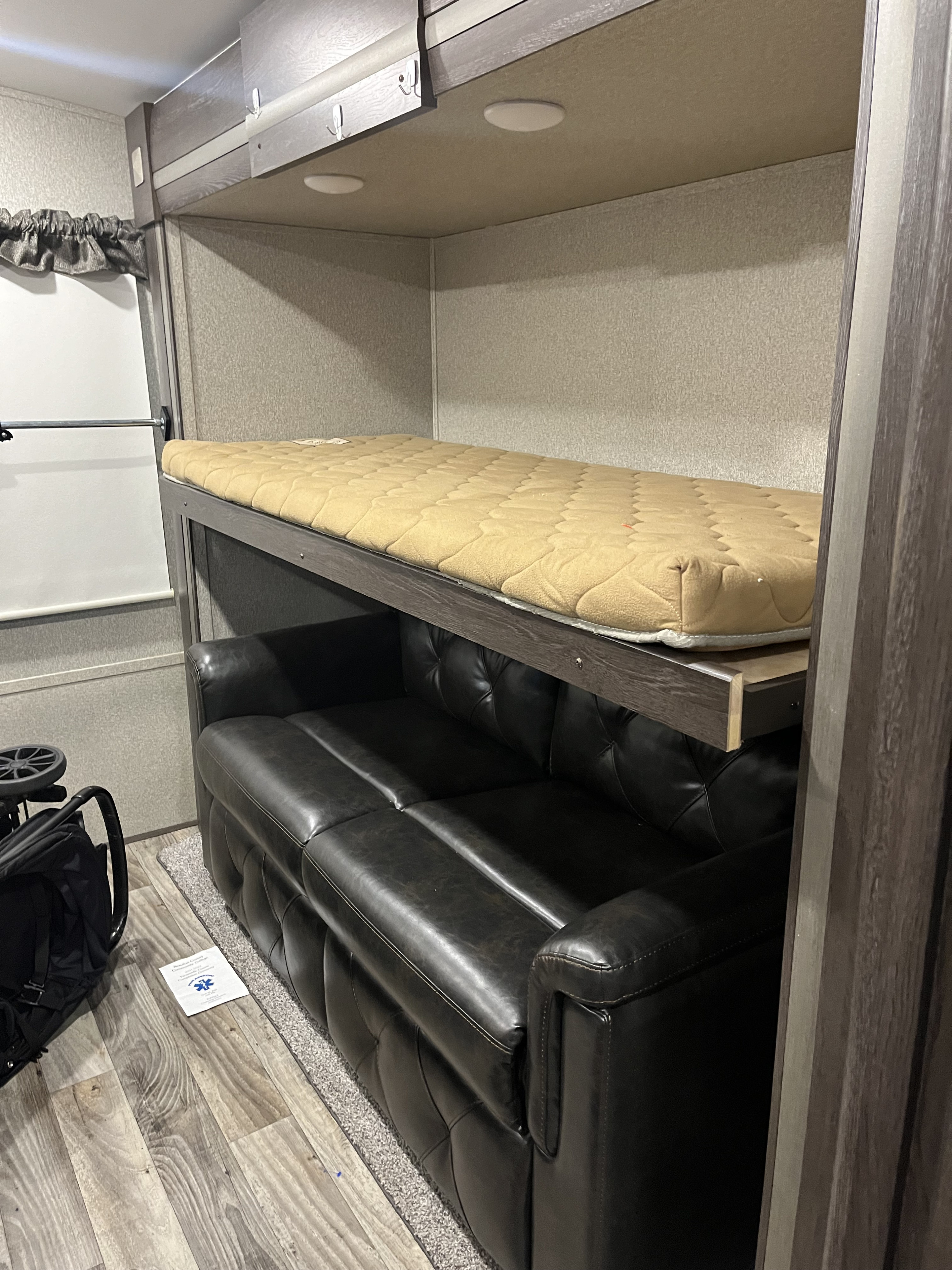 Inside this RV rental, find a space-saving setup: a black leather sofa below a raised bunk bed with a comfy tan mattress.. Keystone RV Outback 2019