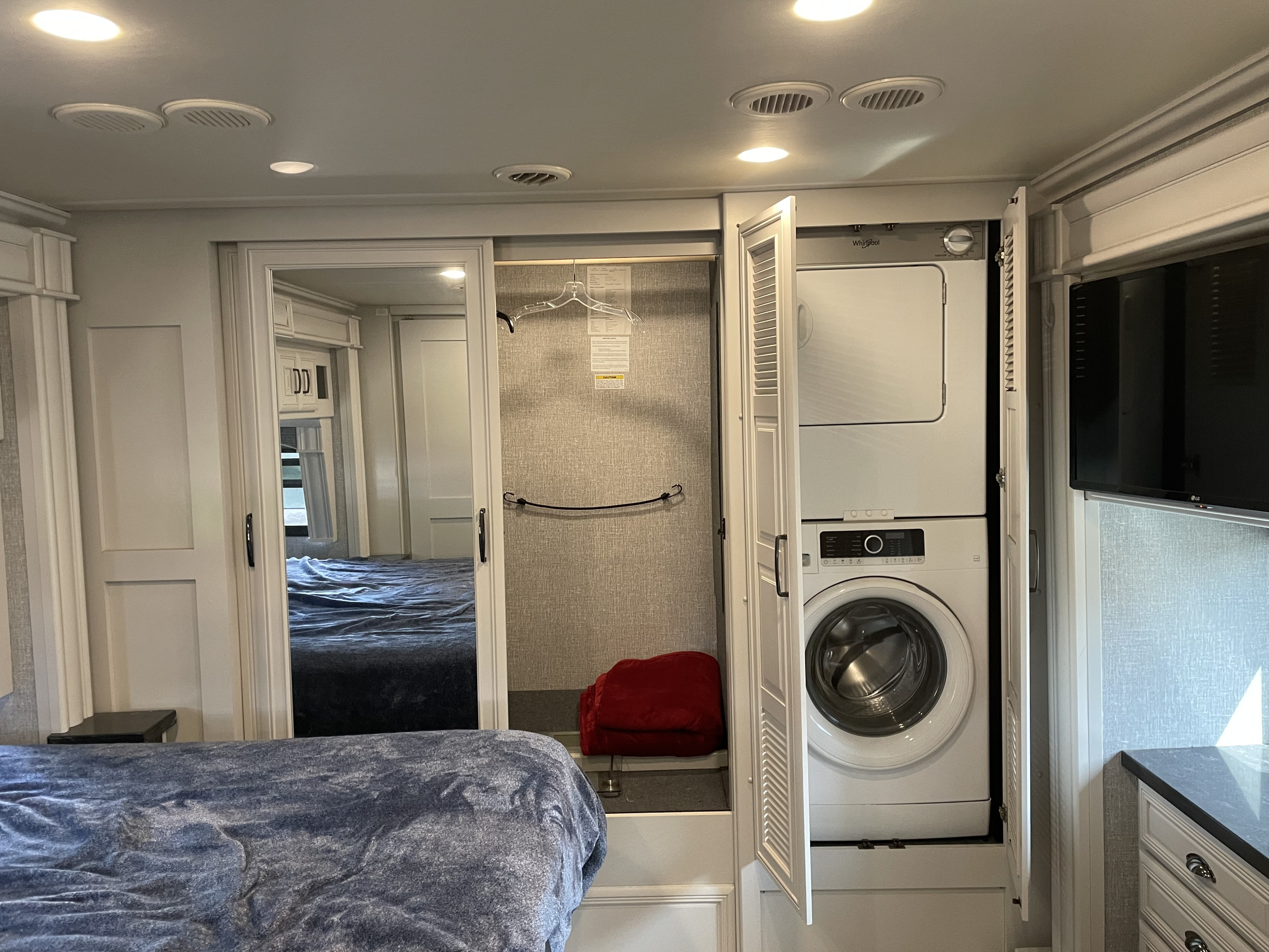 This RV rental's spacious bedroom offers home-like comfort with a stacked washer/dryer, closet, and TV.. Fleetwood Discovery LXE 2021