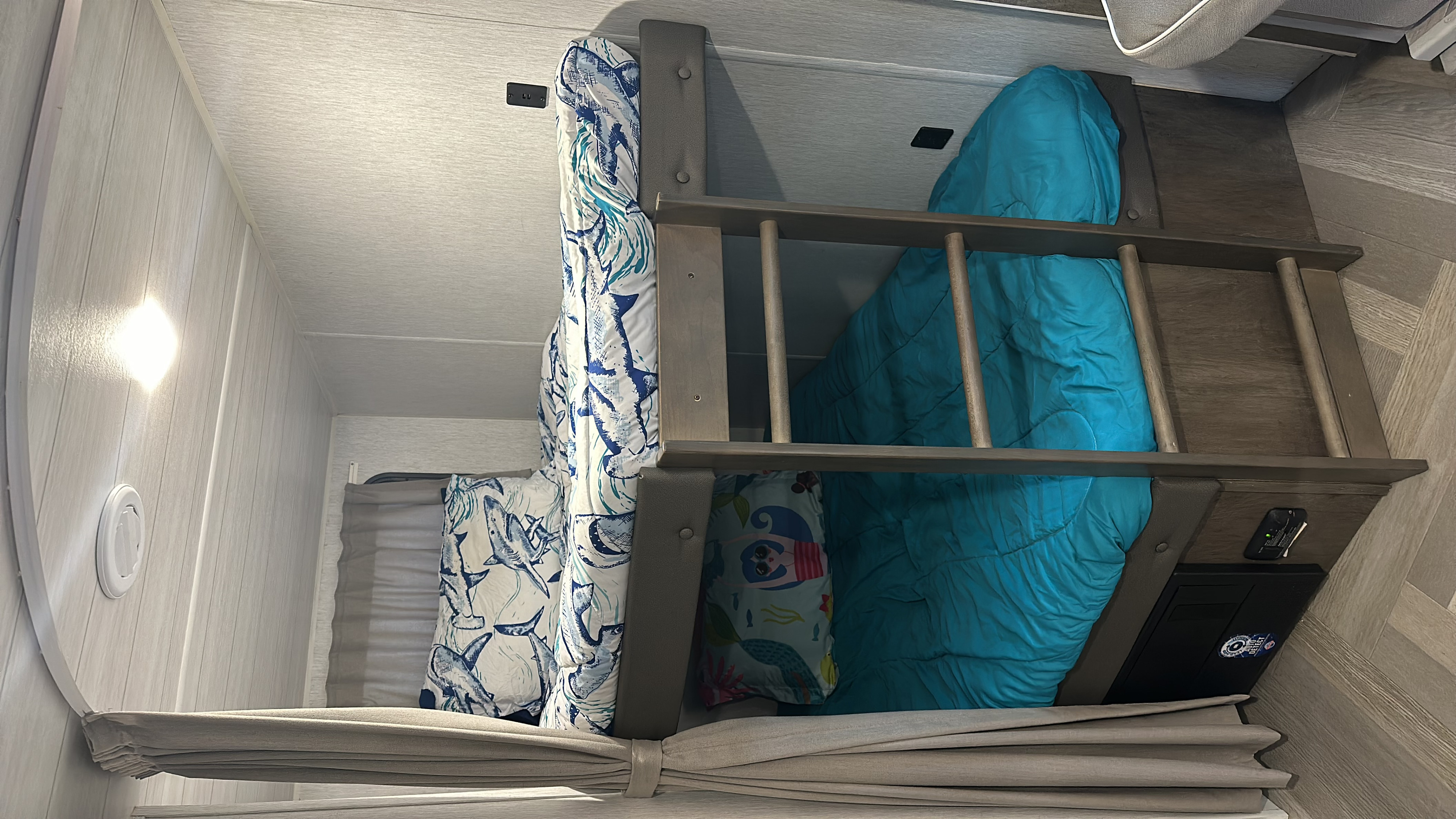 Inside an RV rental: cozy bunk beds with vibrant blue and shark-themed bedding, ideal for family camping.. Forest River Salem Cruise Lite 2023