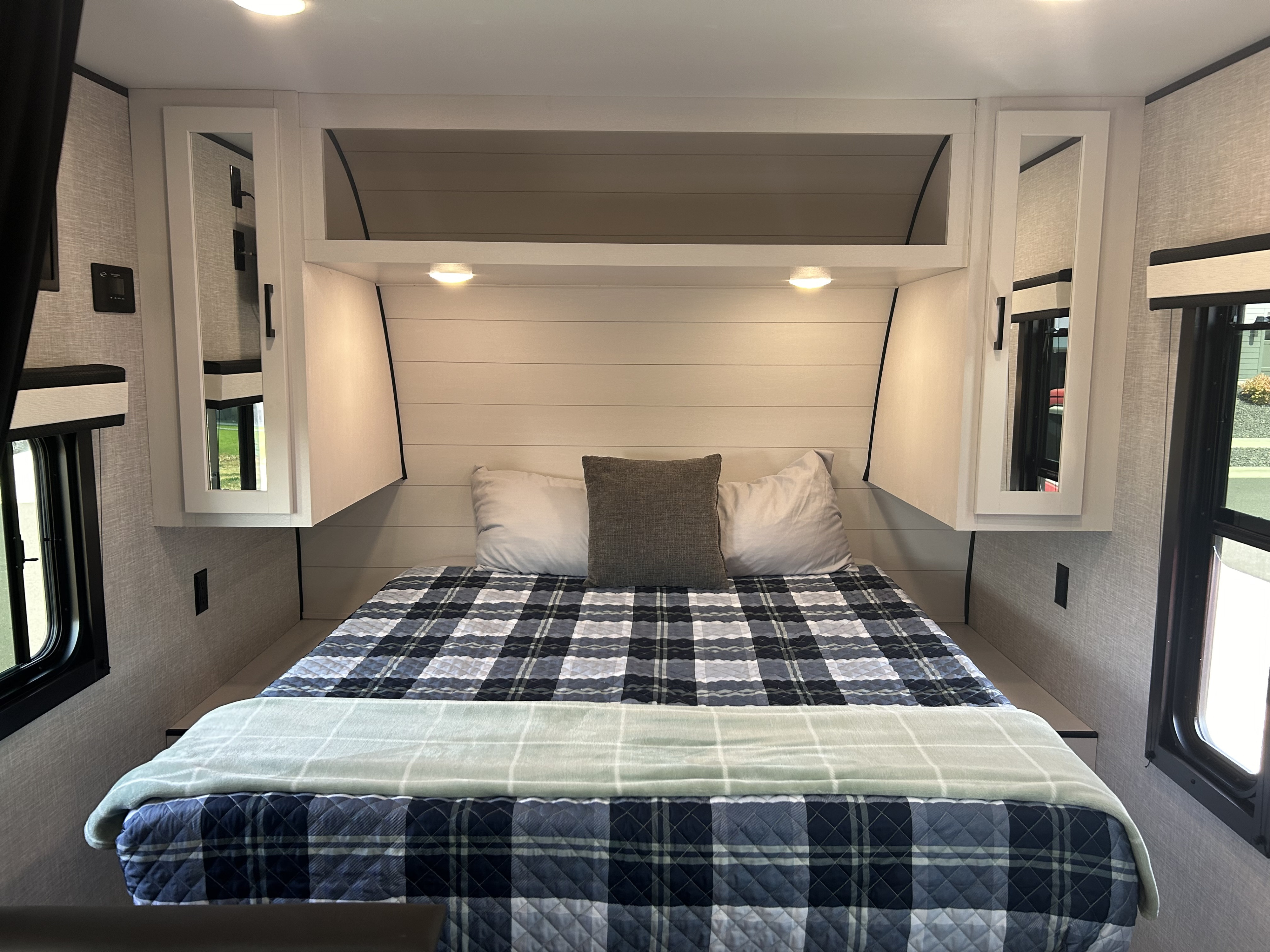 RV rental master bedroom showcasing a plush bed with plaid comforter, mirrored storage, and ambient lighting for a comfy travel stay.. Jayco Jay Flight 2024