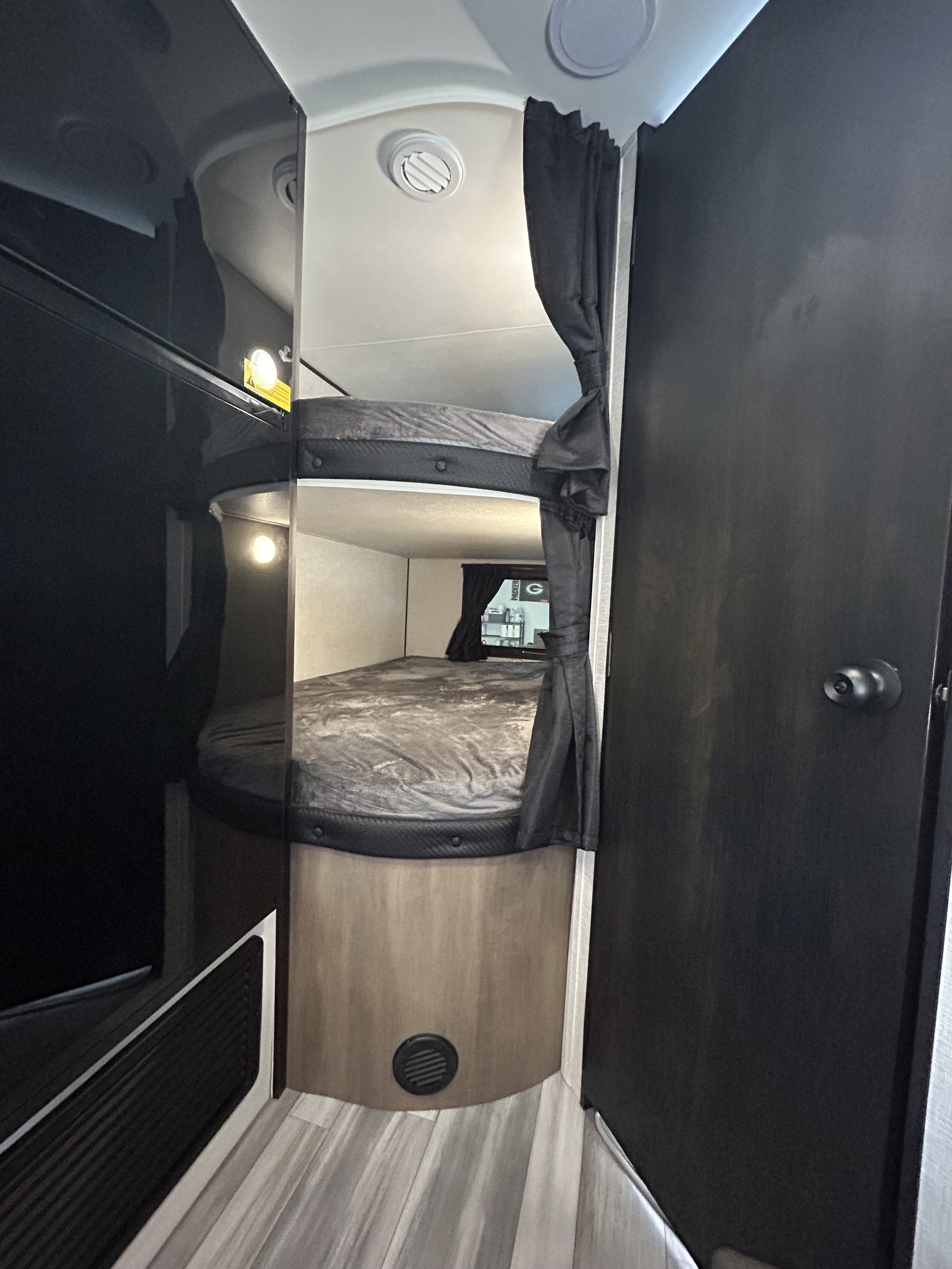 RV rental bunk beds with privacy curtains, showing a compact and functional sleeping area. Features ceiling vents and lighting.. Jayco Jay Flight 2024