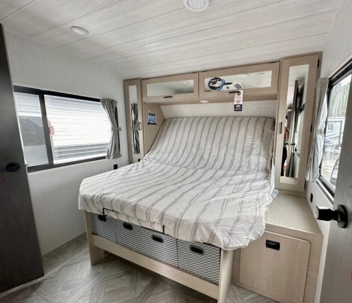 RV rental bedroom interior, featuring a striped bed, overhead storage, and bright windows, perfect for travel comfort.. Forest River Salem 2024