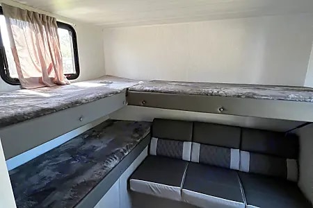 RV rental interior showing bunk beds with gray mattresses & a gray/black bench seat for comfortable travel.. Forest River Salem Cruise Lite 2024