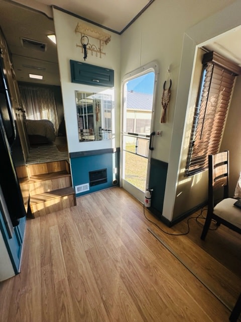 Inside an RV rental: welcoming entrance area with light wood floors and stairs to the elevated sleeping quarters.. Holiday Rambler Presidential 2006