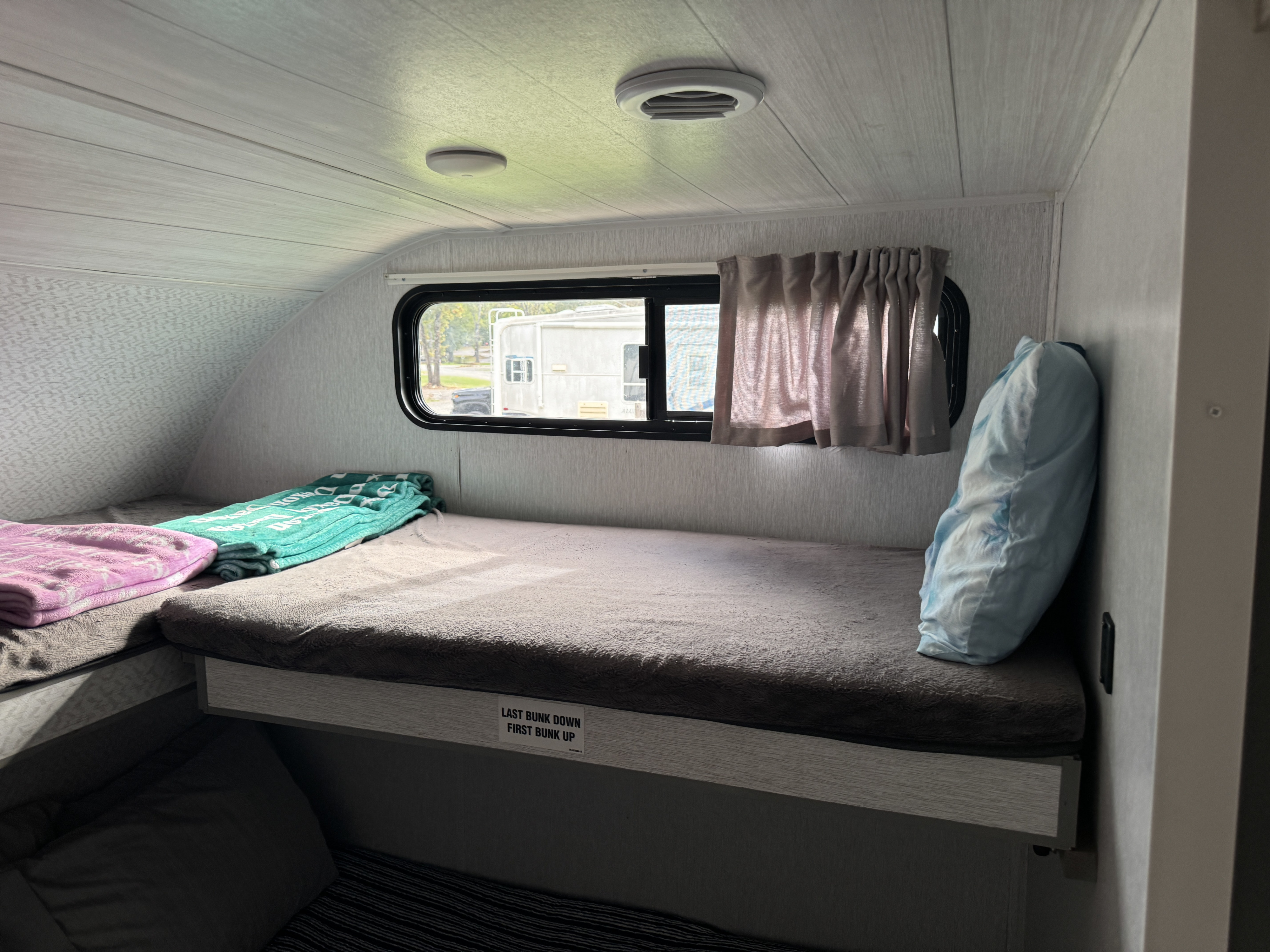 RV rental: Bright interior featuring cozy bunk beds with colorful blankets and a pillow, ideal for travel comfort.. Forest River Wildwood 2023