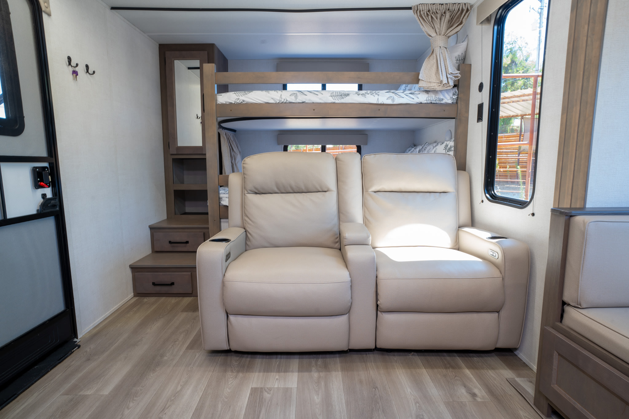 Light-filled RV rental interior featuring plush recliners, sturdy bunk beds, and modern storage steps.. Grand Design Transcend Xplor 2024