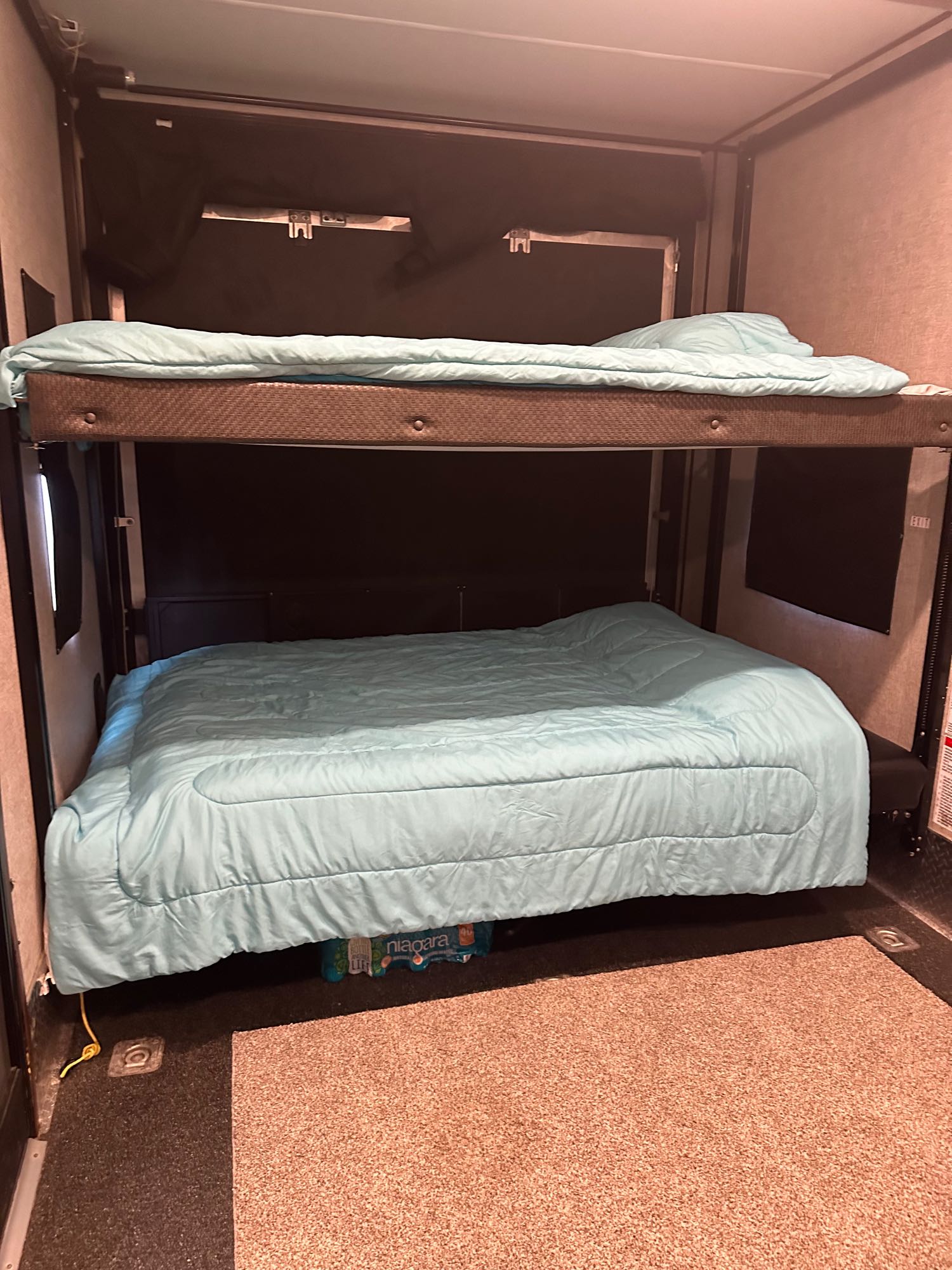 RV rental features two bunk beds with aqua comforters. The lower bed is made, while the upper bed is folded up, saving space.. Forest River Vengeance 2019
