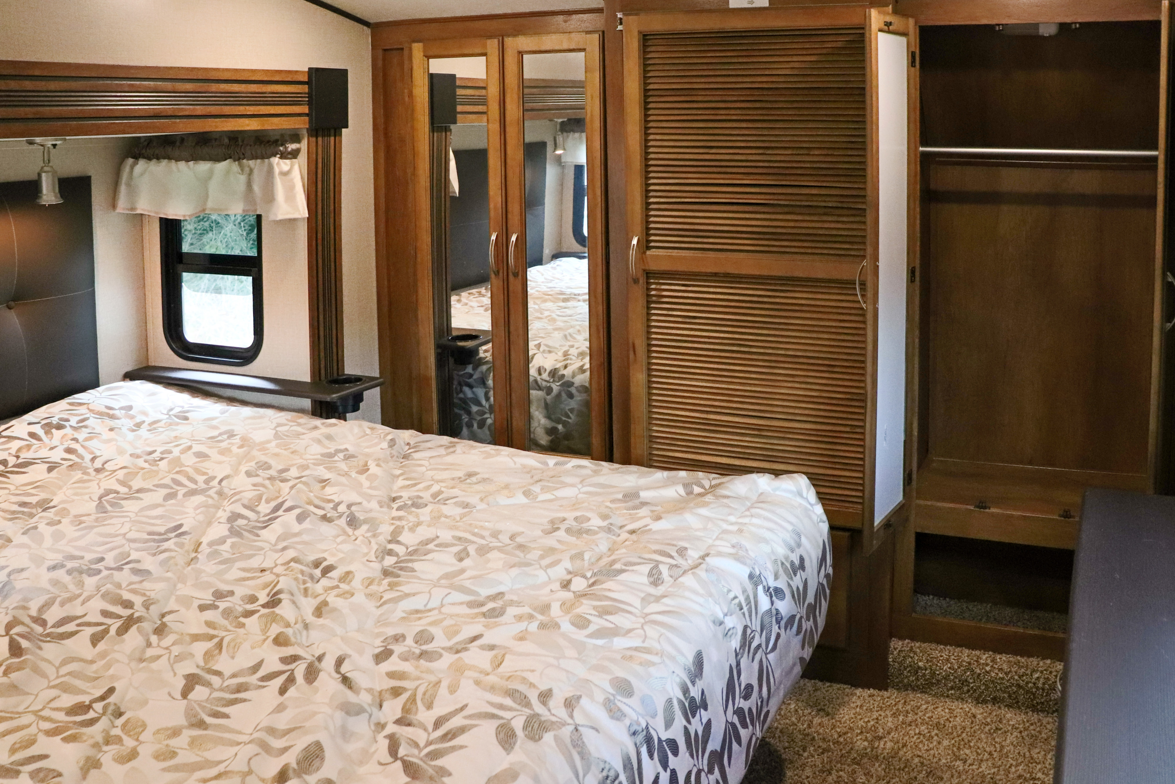 RV rental bedroom with a comfortable bed, leafy comforter, and ample built-in mirrored and louvered closet storage.. Forest River Coachmen Chaparral 2018