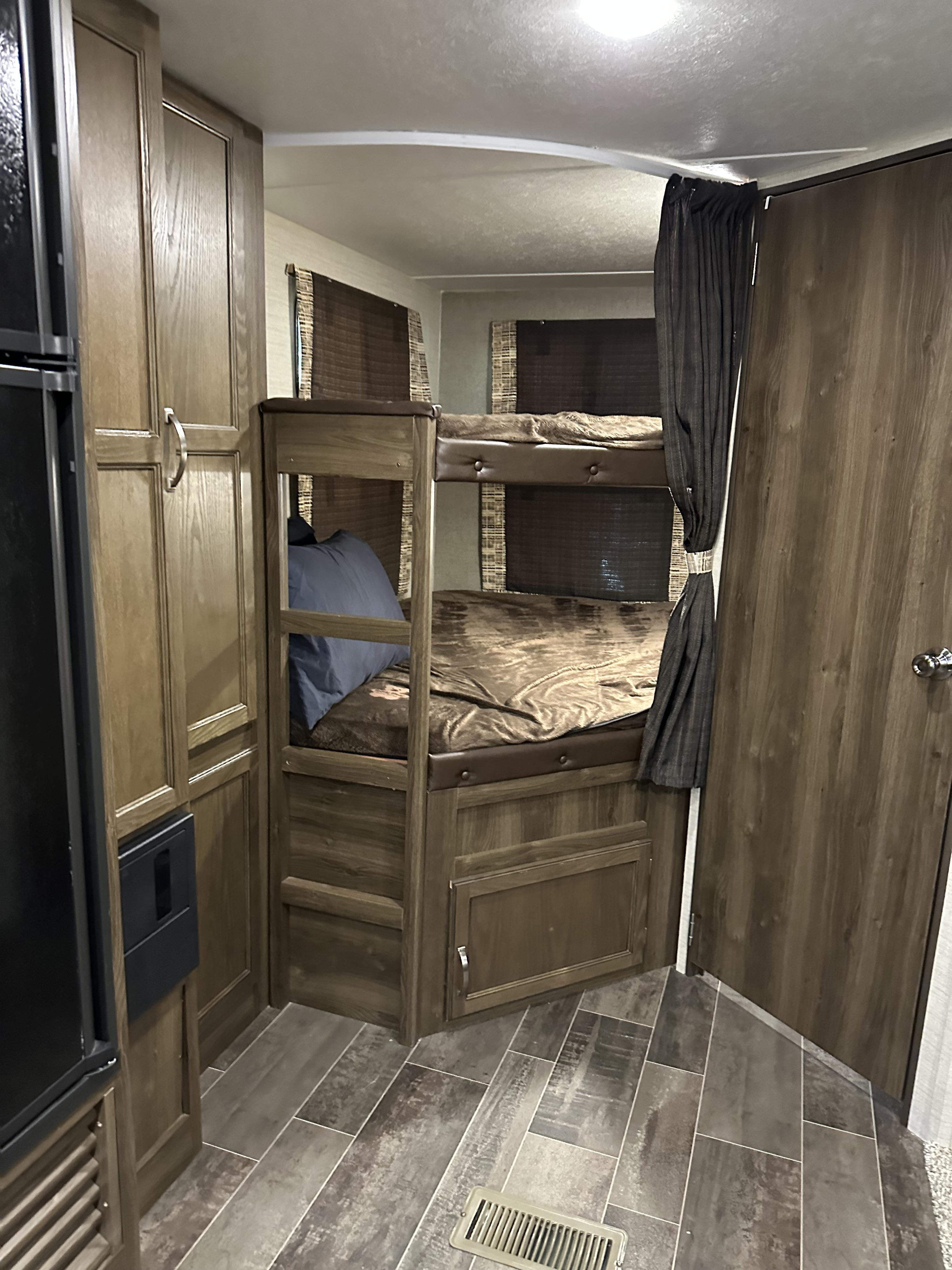 RV rental interior showcasing wooden bunk beds, a refrigerator, and built-in storage cabinets for a travel-ready home.. Keystone RV Bullet Ultra Lite 2018