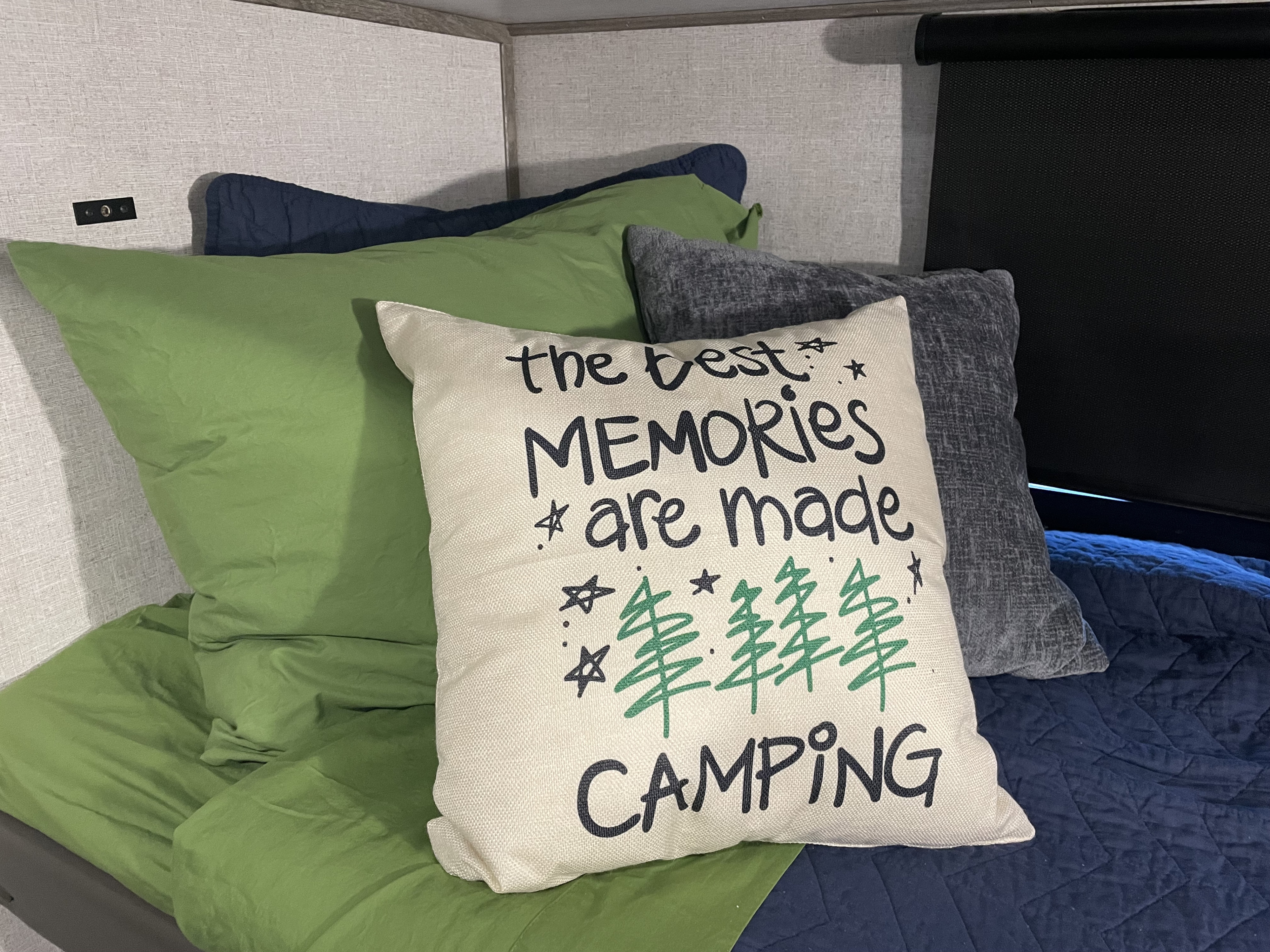 RV rental interior featuring a cozy bunk bed with green sheets, blue quilt, and a fun "Camping" pillow.. Forest River Salem Hemisphere 2021