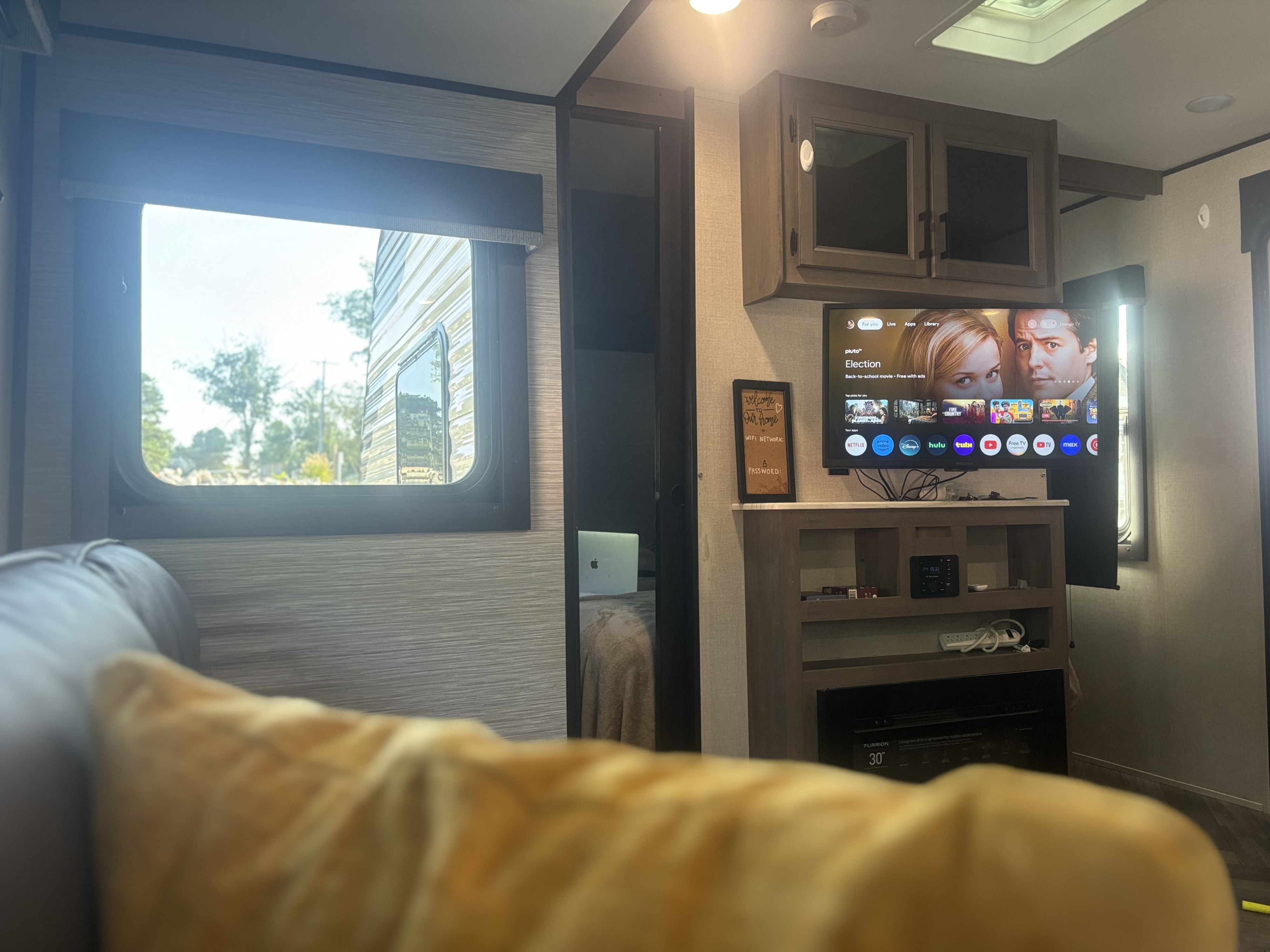 Relaxing RV rental living space with a large TV, WiFi sign, and bright window view, perfect for entertainment.. Highland Ridge RV Olympia 2022