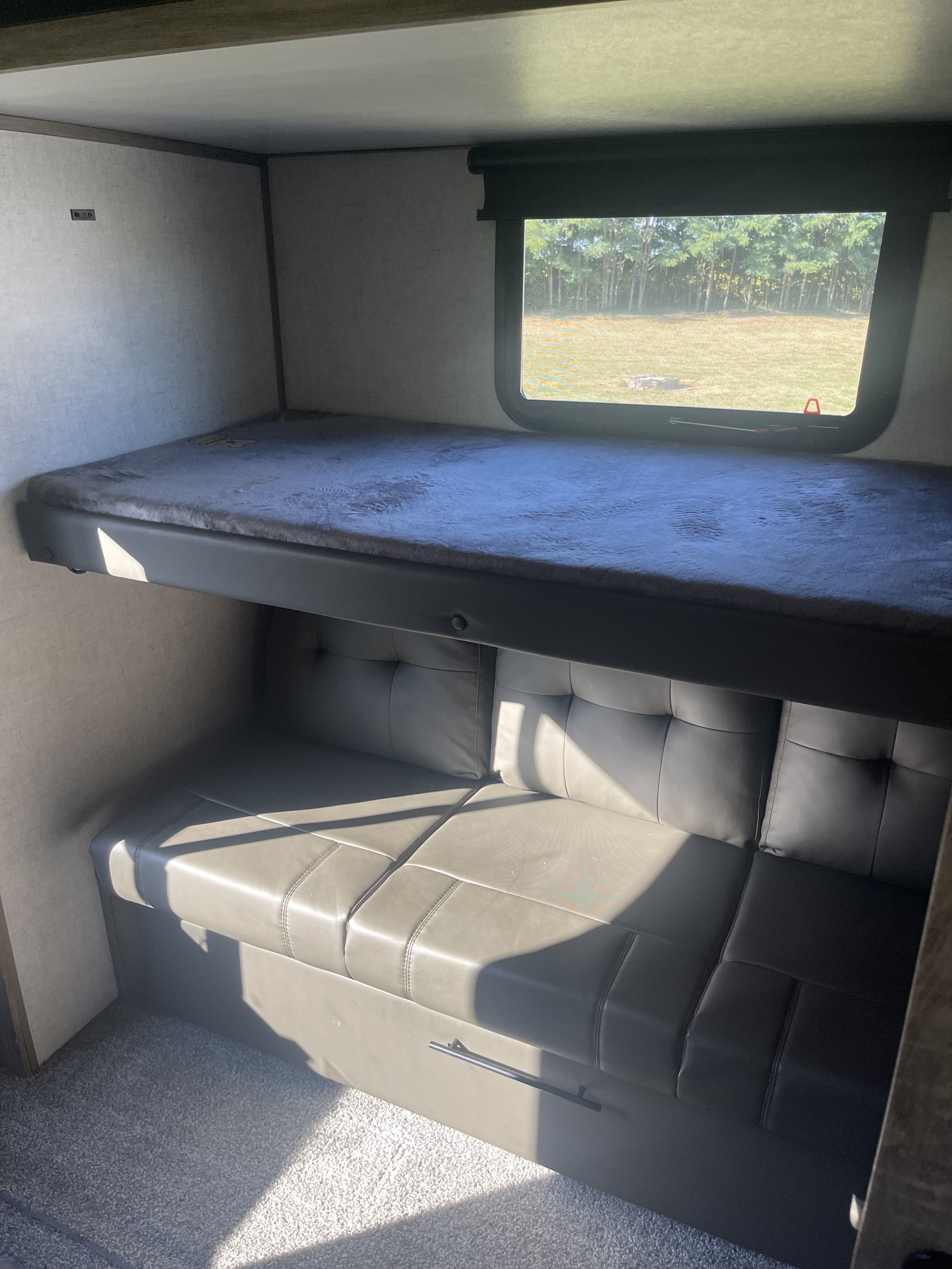 RV rental interior featuring comfortable bunk beds, a convertible sofa, and a window offering a scenic outdoor view.. Forest River Salem Hemisphere 2020