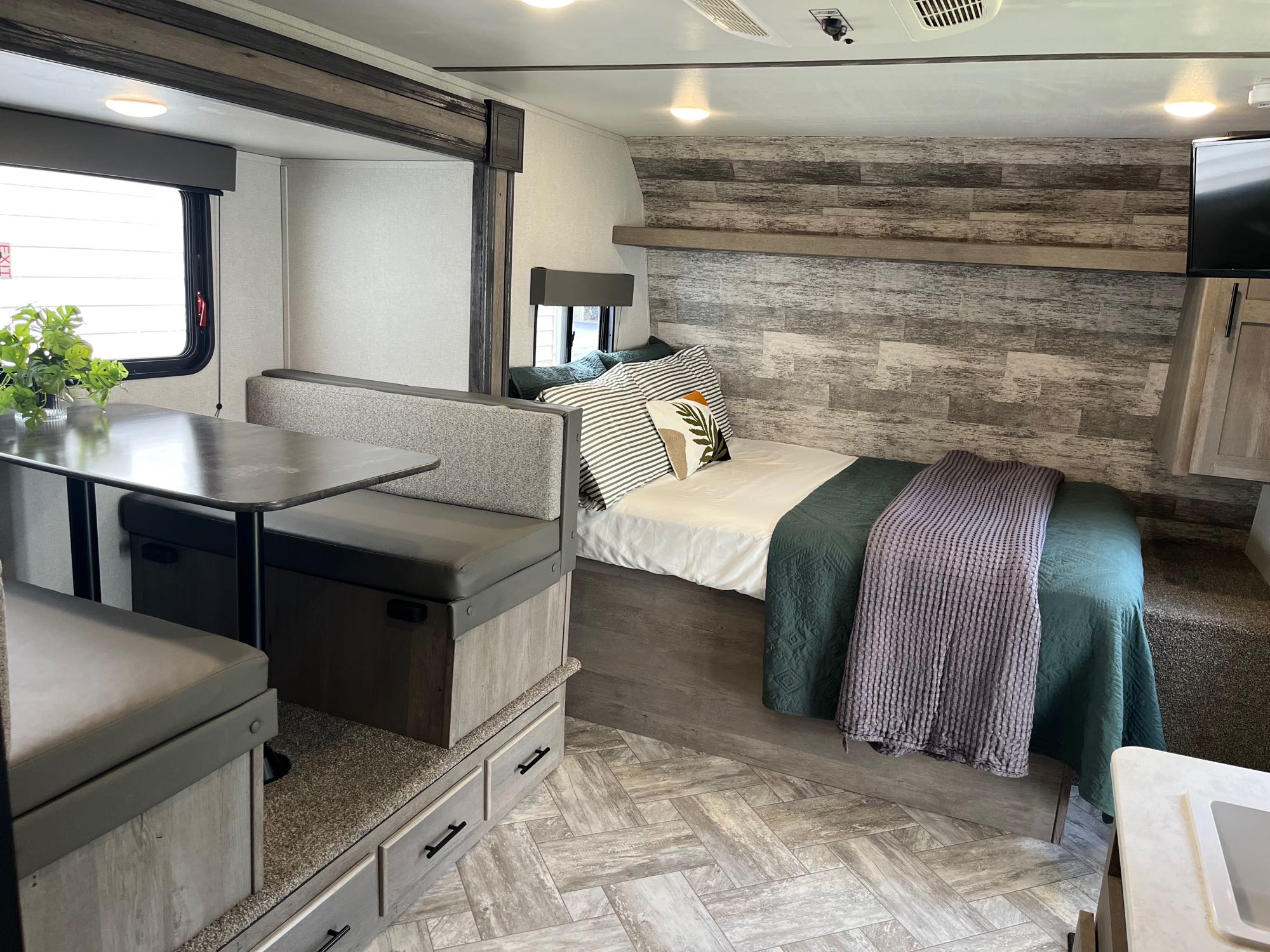 Modern RV rental interior with a cozy bedroom and dinette area, featuring sleek storage and stylish decor.. Keystone RV Springdale 2021