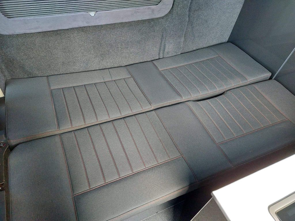 RV rental: two dark grey upholstered cushions with red stitching, forming a cozy bed or seating area in a camper van.. Citroen Jumper 2021