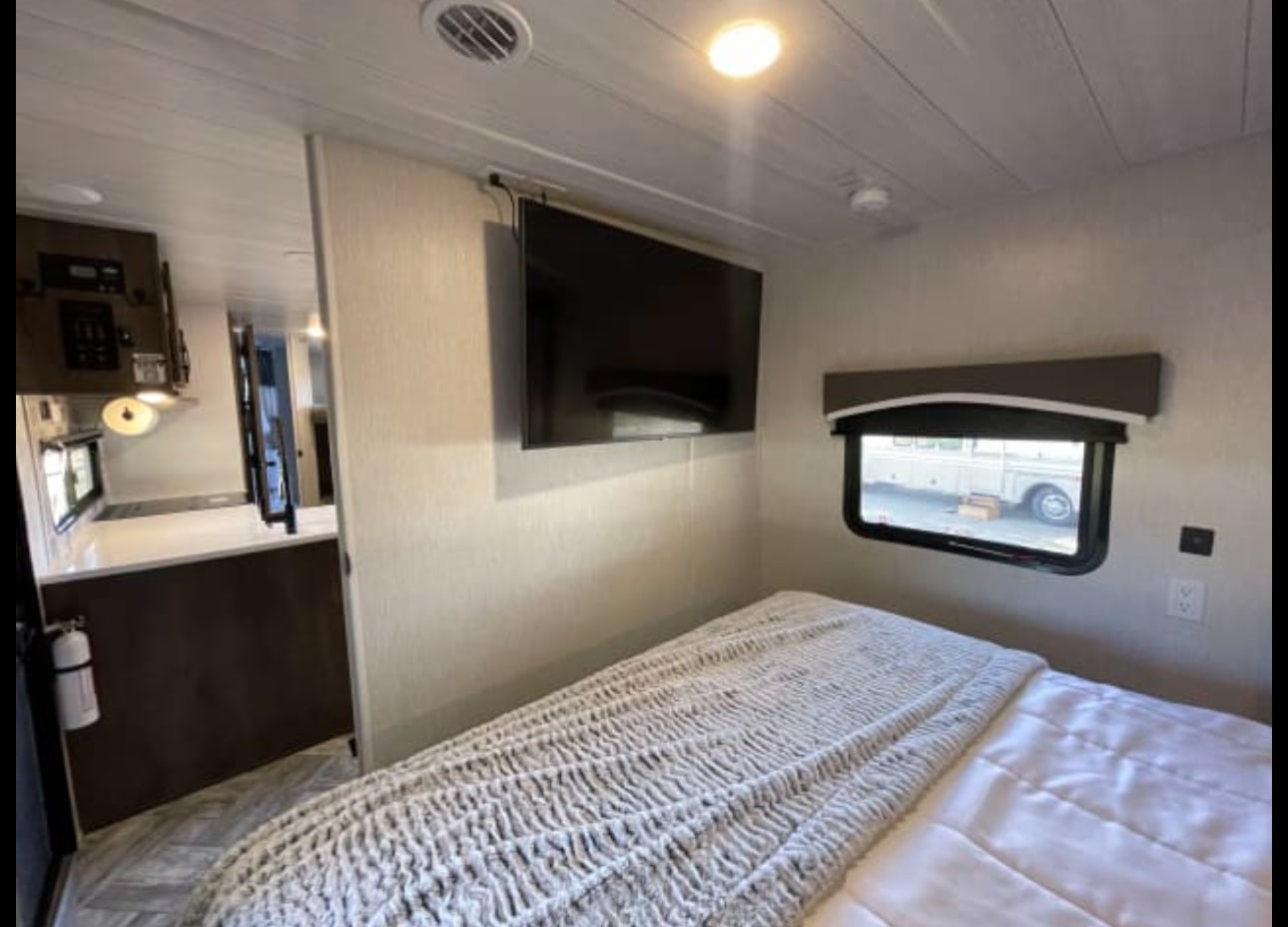 Explore this comfy RV rental interior, featuring a bedroom with TV, window, and an adjoining kitchen area. Your home on wheels awaits!. Forest River Evo T2490 2022