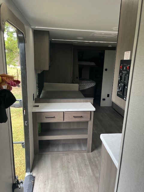 RV rental interior: entryway, storage/counter, dinette, and glimpse of bunk beds in this modern space.. Grand Design Transcend Xplor 2024