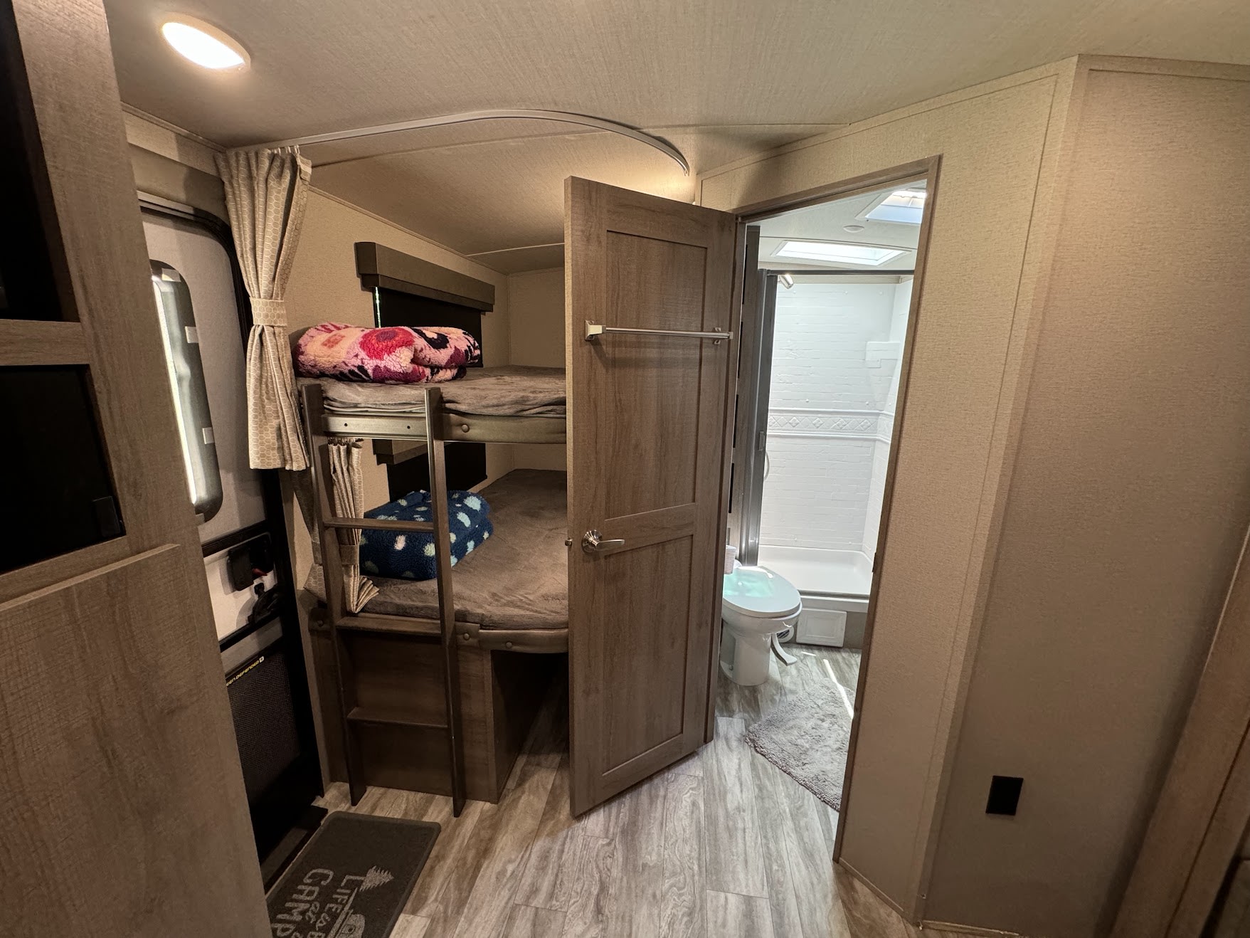 This RV rental interior features comfortable bunk beds with a ladder & a compact bathroom with toilet and shower.. Grand Design Imagine 2021