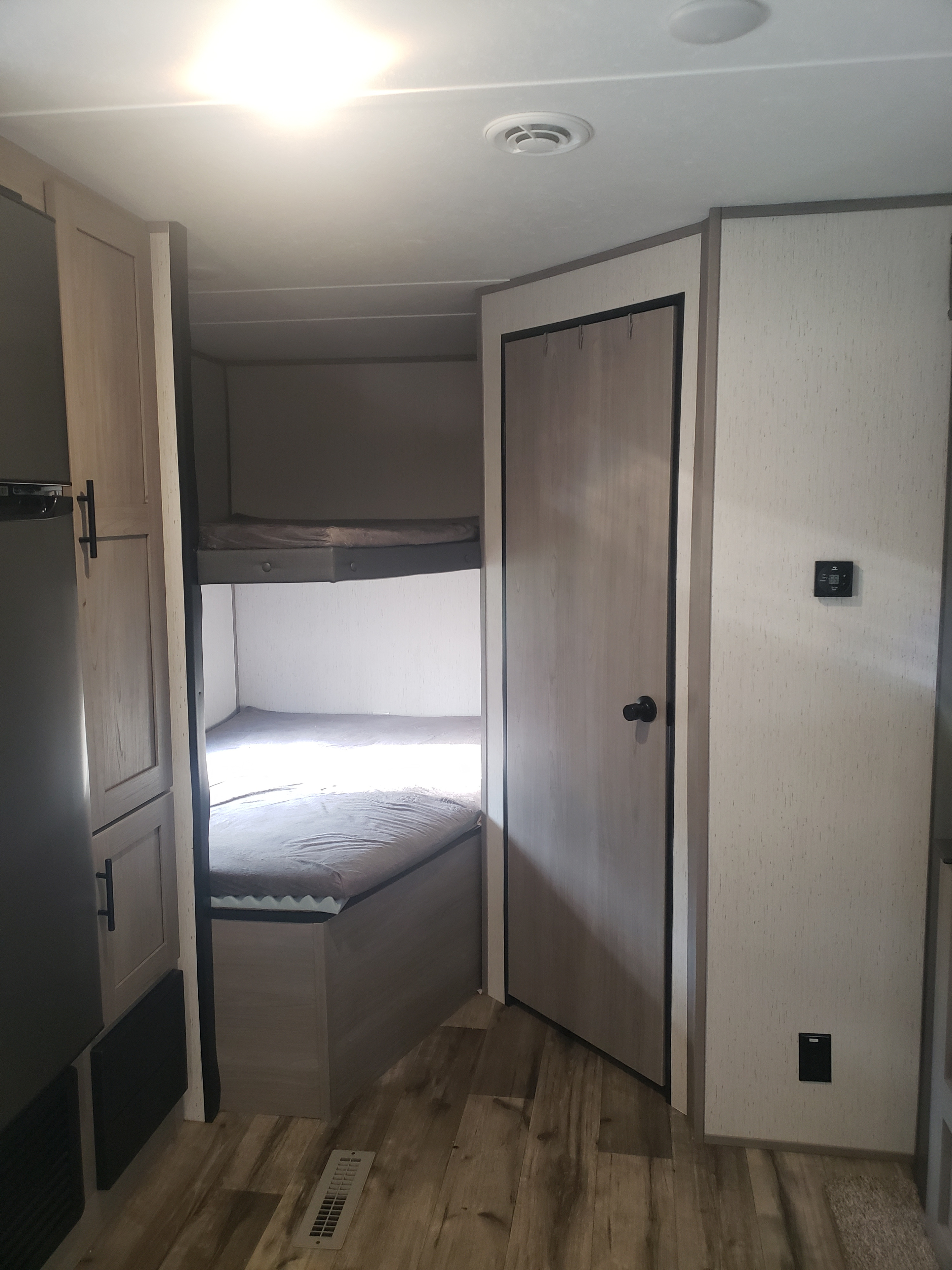 RV rental interior features bunk beds, a storage cabinet, and a large wardrobe on wood-look flooring.. Dutchmen Coleman Lantern LT 2022